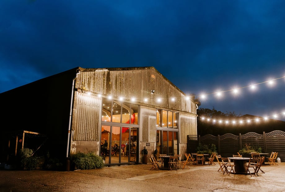 Industrial-chic wedding venue, The Field at Lodge Farm with atmospheric terrace bistro lighting.