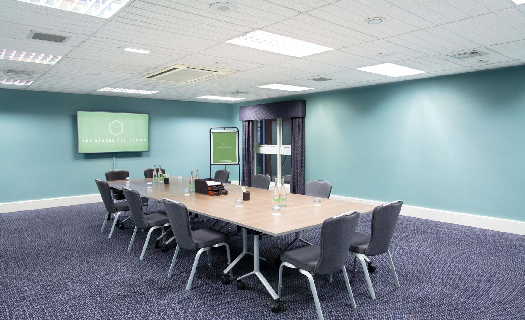 Boardroom-style breakout area with modular tables for corporate meetings and training sessions.