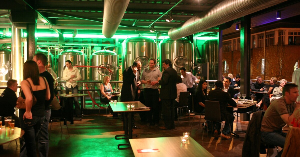 Industrial-chic brewery venue with green uplighting for corporate networking and social events.