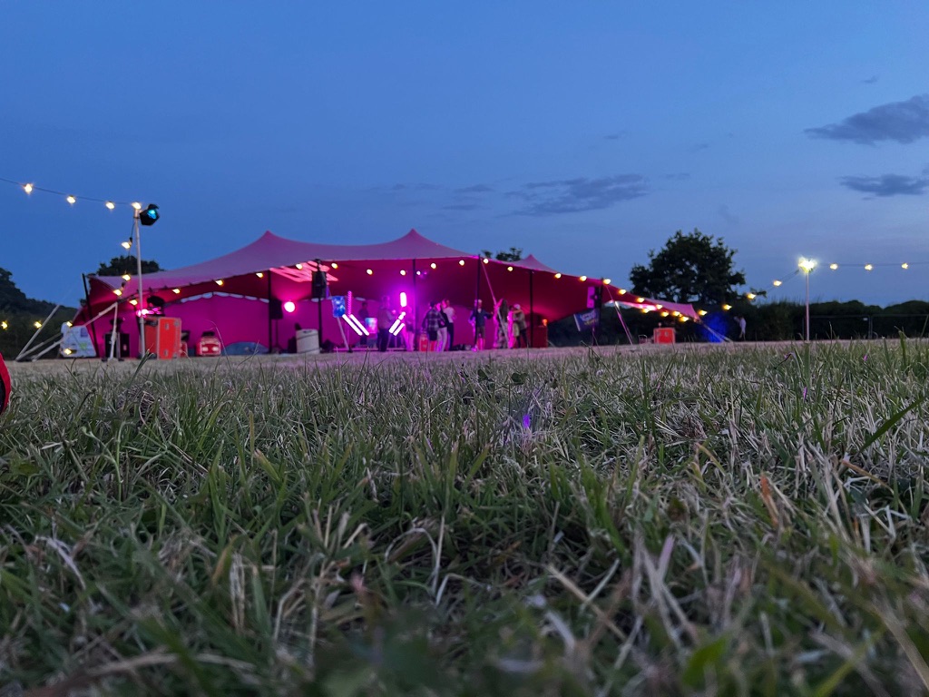 Stretch tent at Sussex meadow party: outdoor festival lighting and corporate event venue.