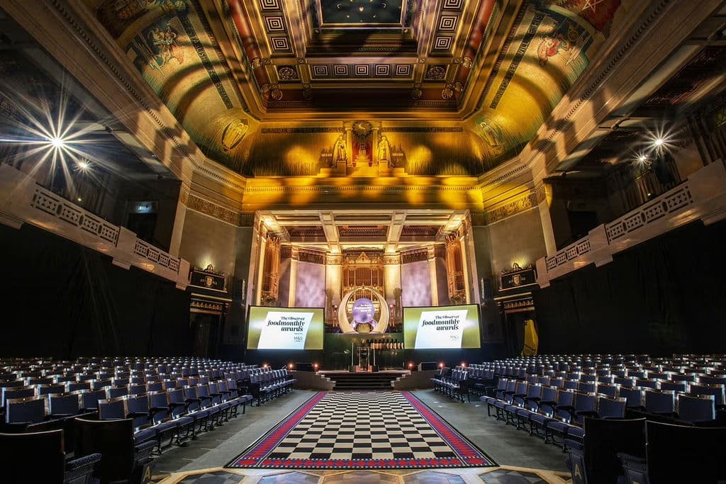 Theater-style awards ceremony in historic Grand Temple with dramatic stage lighting.