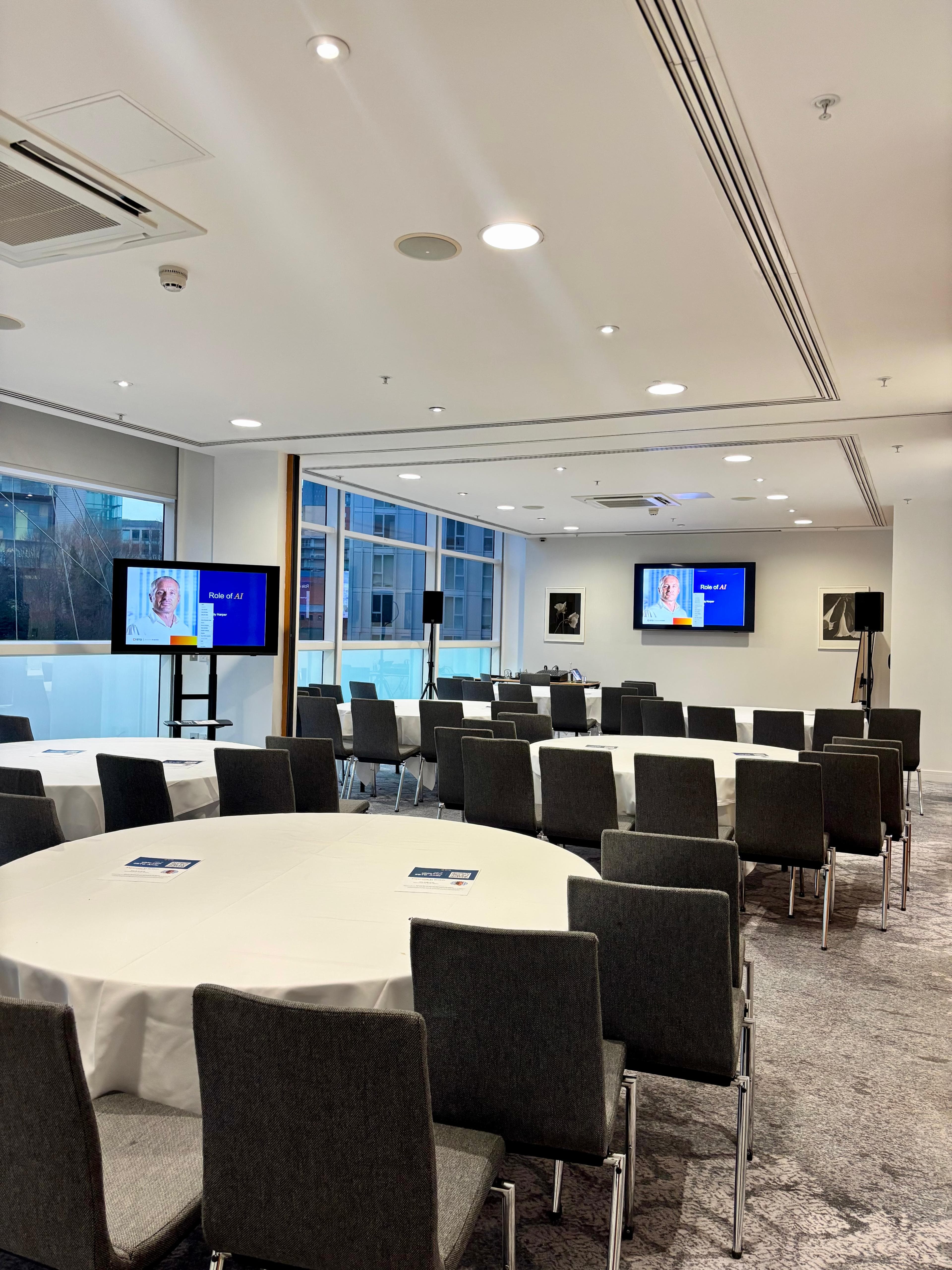 Hybrid corporate meeting room setup with round tables at The Lowry Hotel for professional events.