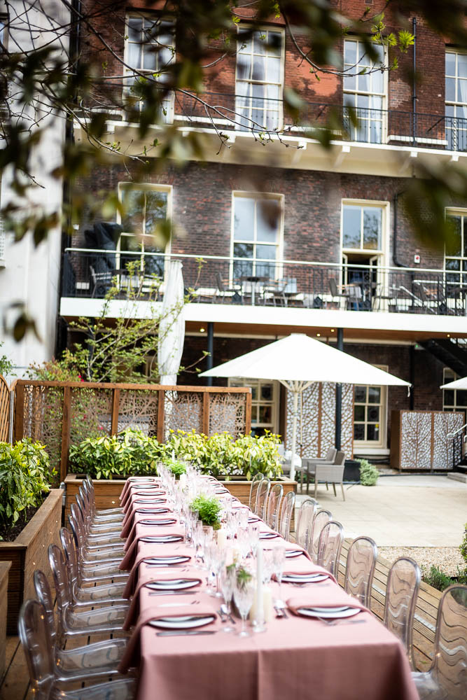 Elegant outdoor event space with table setting, greenery, and umbrellas at Six Park Place.