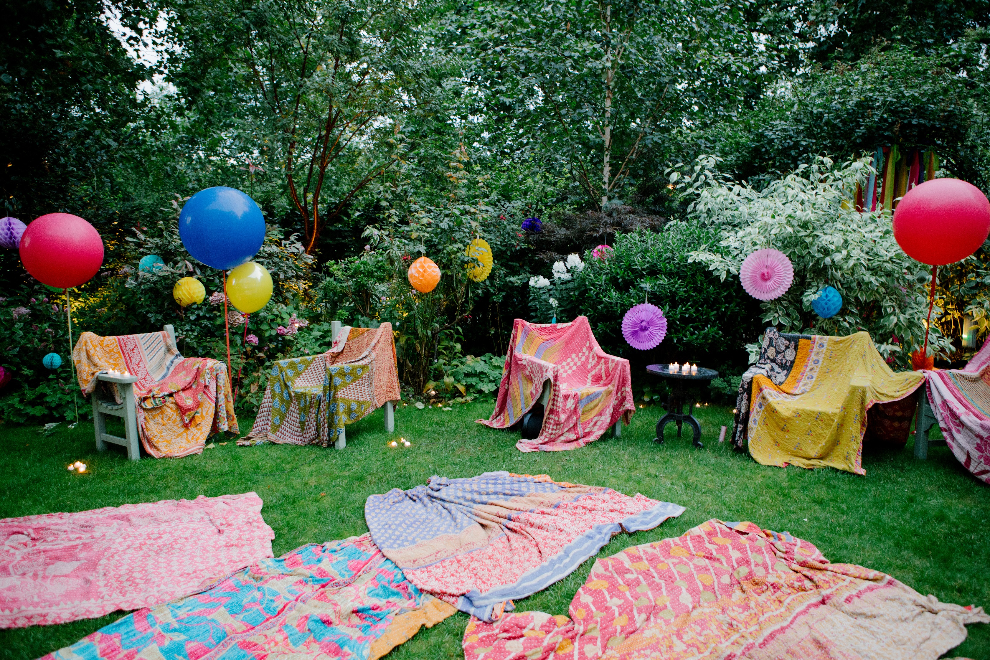 Vibrant outdoor event setup with colorful textiles and balloons in Six Park Place garden.