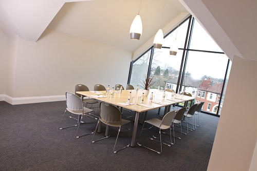 Modern meeting room with large table and natural light, ideal for collaboration events.