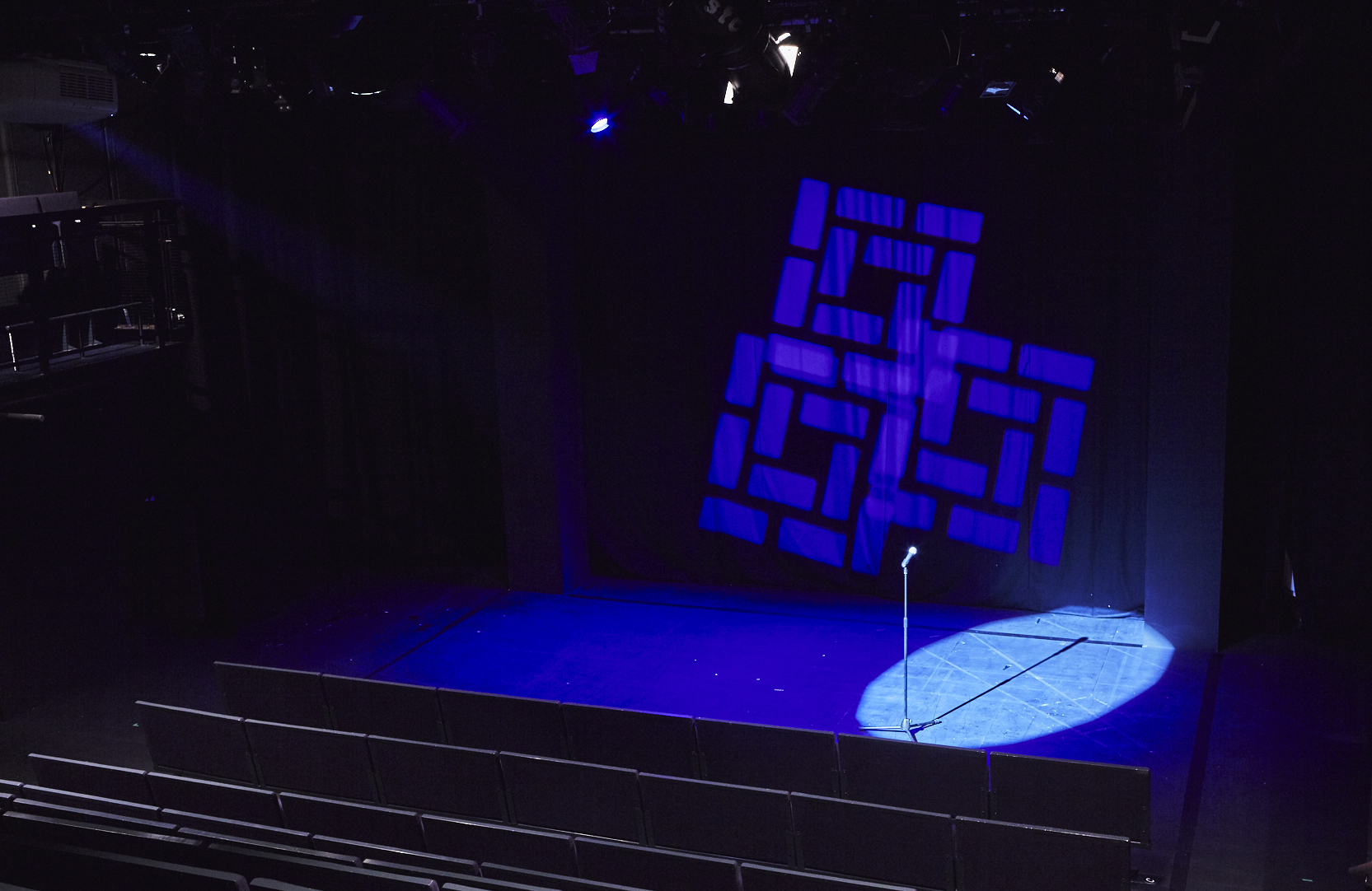 Main House Theatre stage with spotlight on microphone, ideal for performances and presentations.