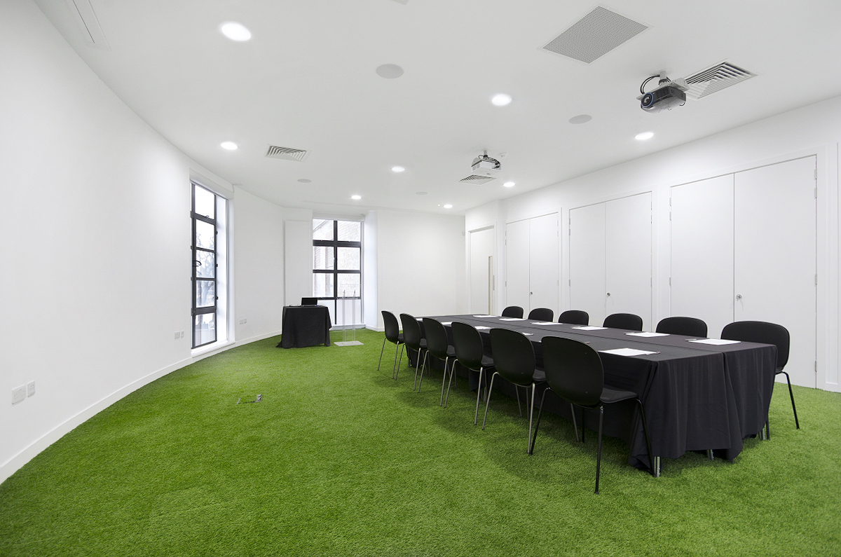 Modern conference room with long table, green carpet for workshops at Museum of Brands.
