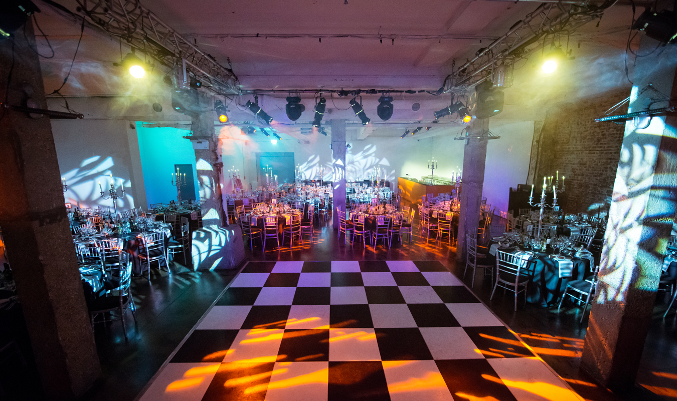 Elegant event space with round tables and a black-and-white dance floor for galas.