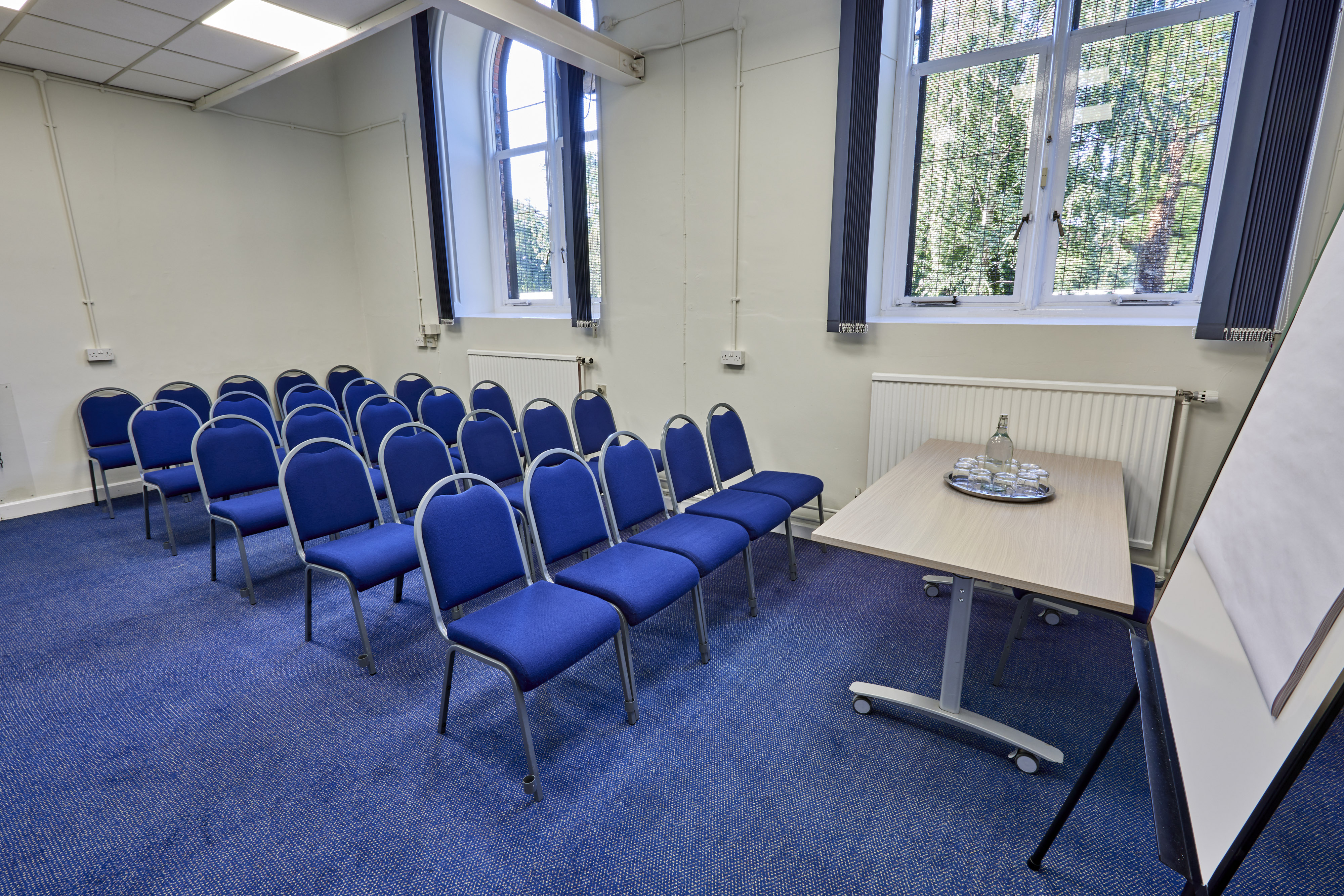 Mambu Room in St Thomas Centre with blue chairs, ideal for workshops and conferences.