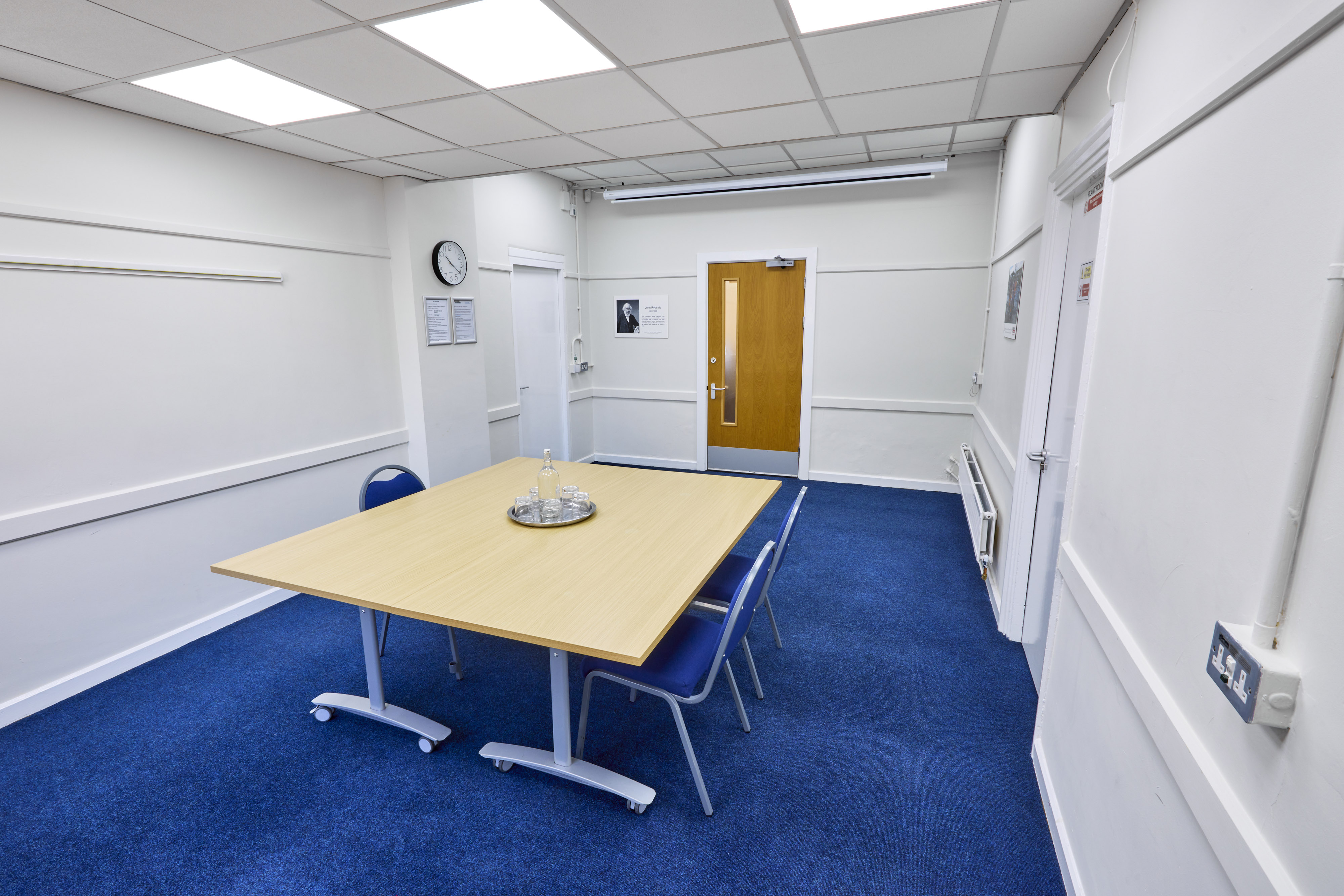 "Rylands Room at St Thomas Centre: bright meeting space with blue carpet for small gatherings."