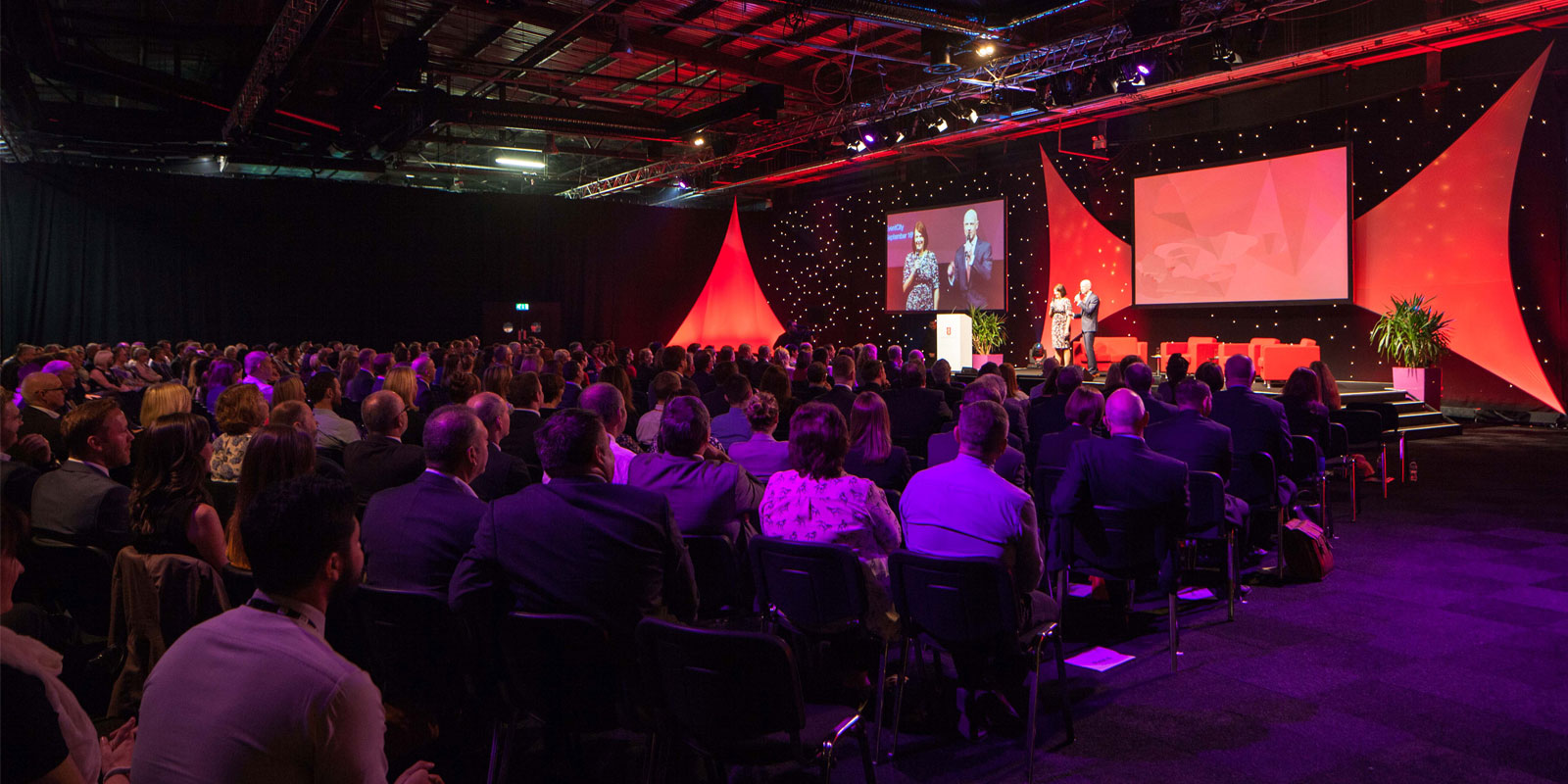 Large audience at corporate event in Hall 4, EventCity; engaging staging and lighting.