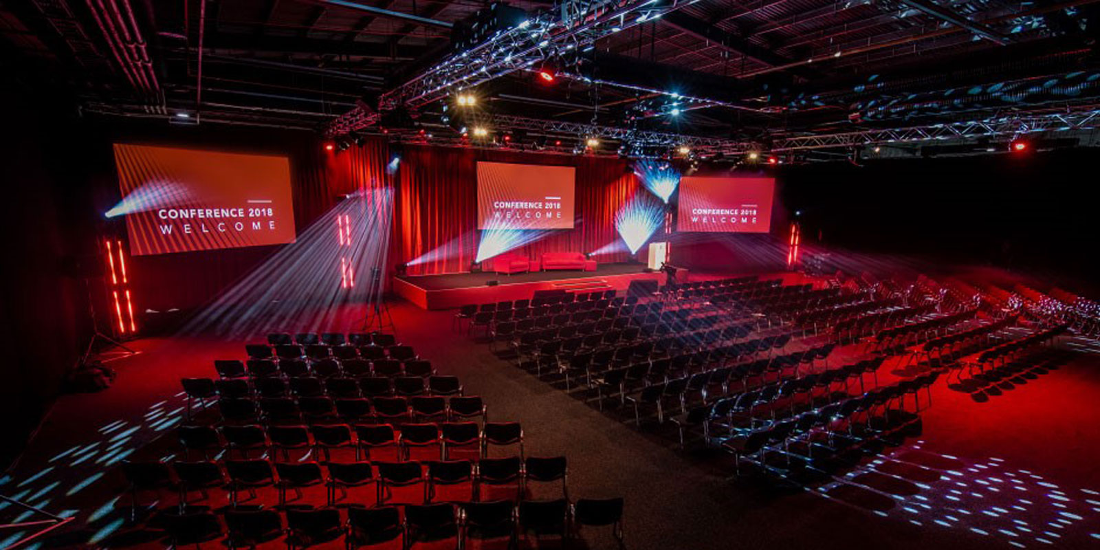 "Spacious Hall 4 conference setup with dynamic lighting and welcoming stage signage."