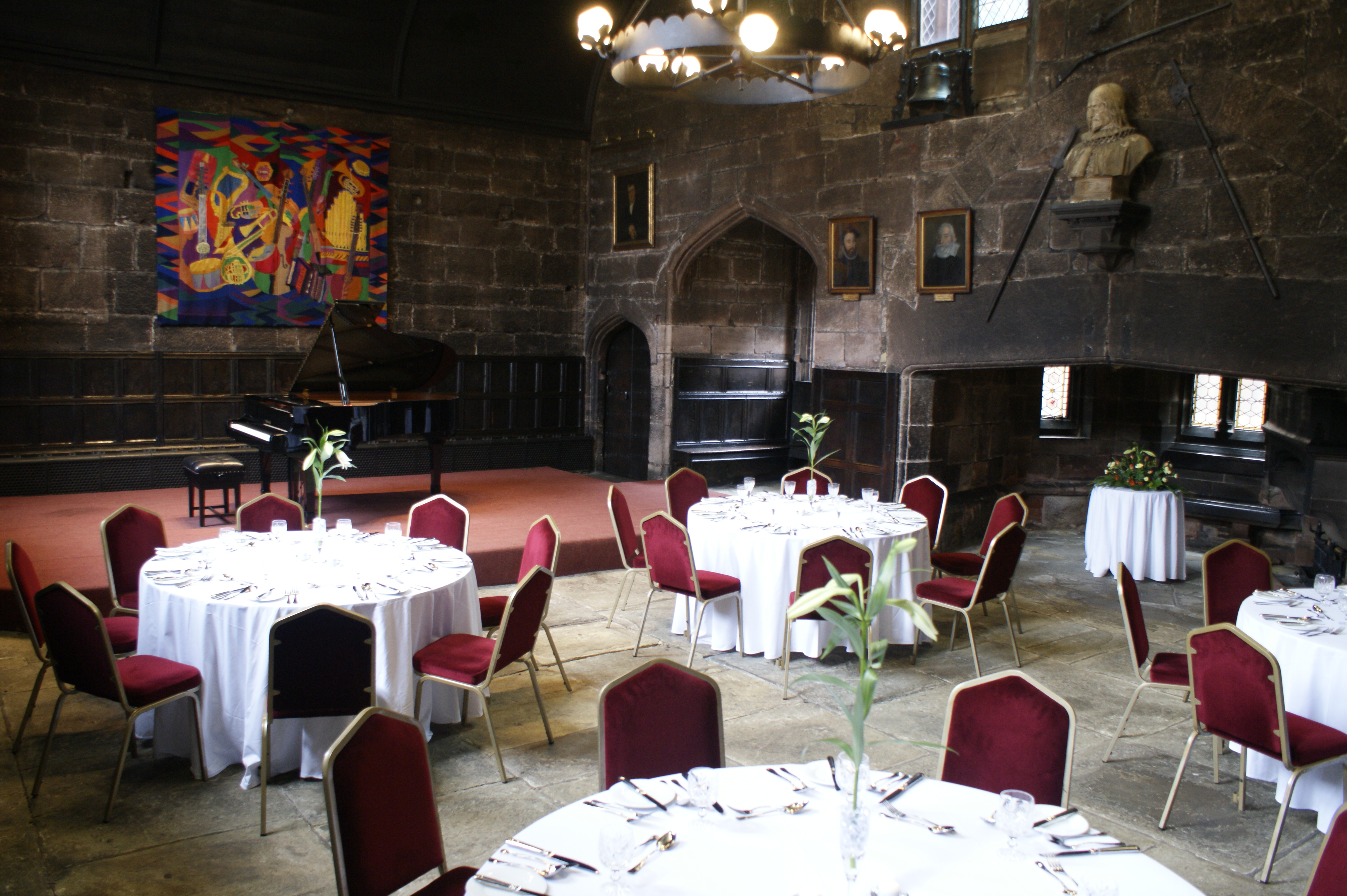 Baronial Hall at Chetham's Library, elegant event space with round tables and red chairs.