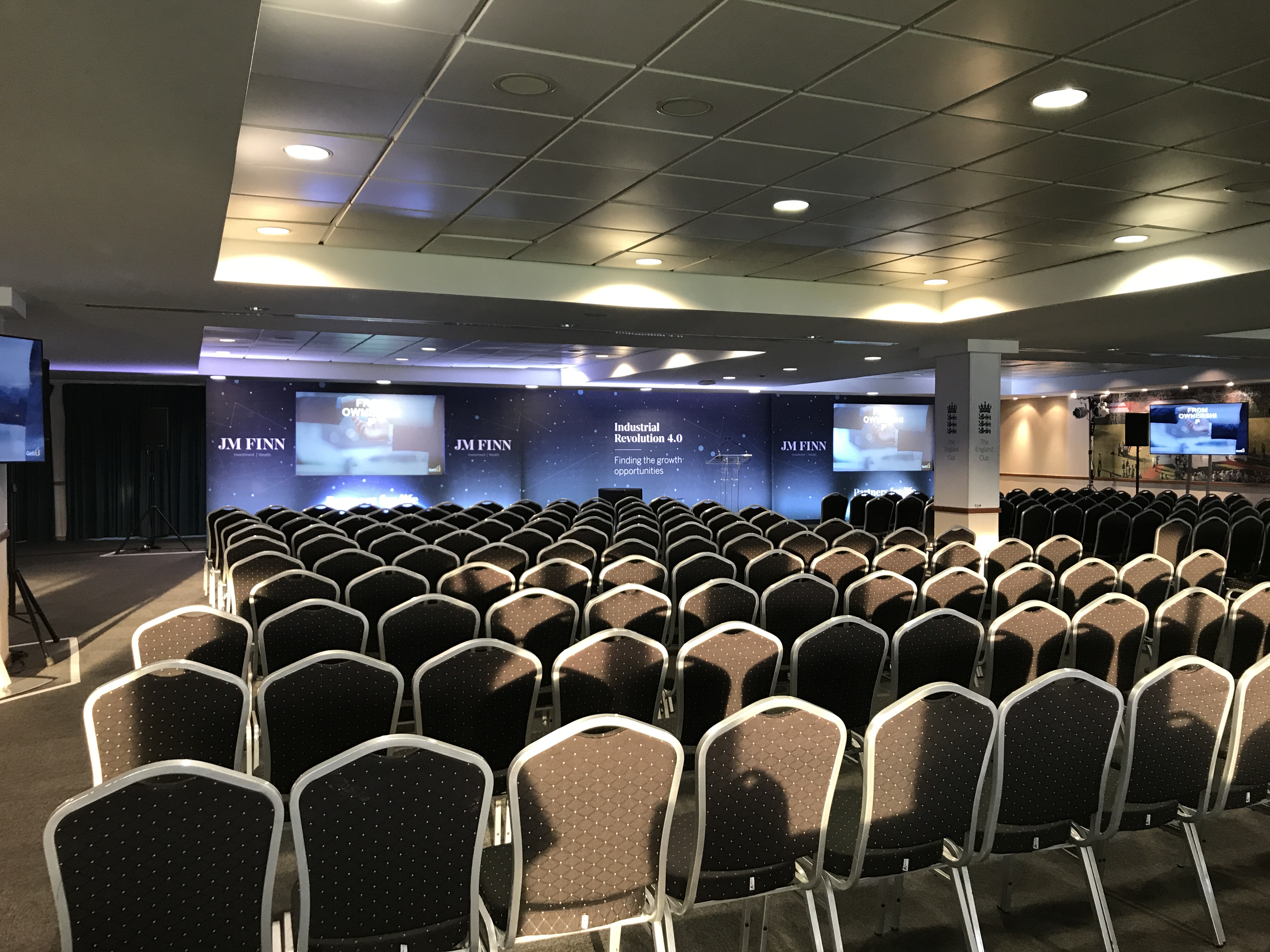 Kia Oval England Room conference setup with chairs and stage for corporate events.