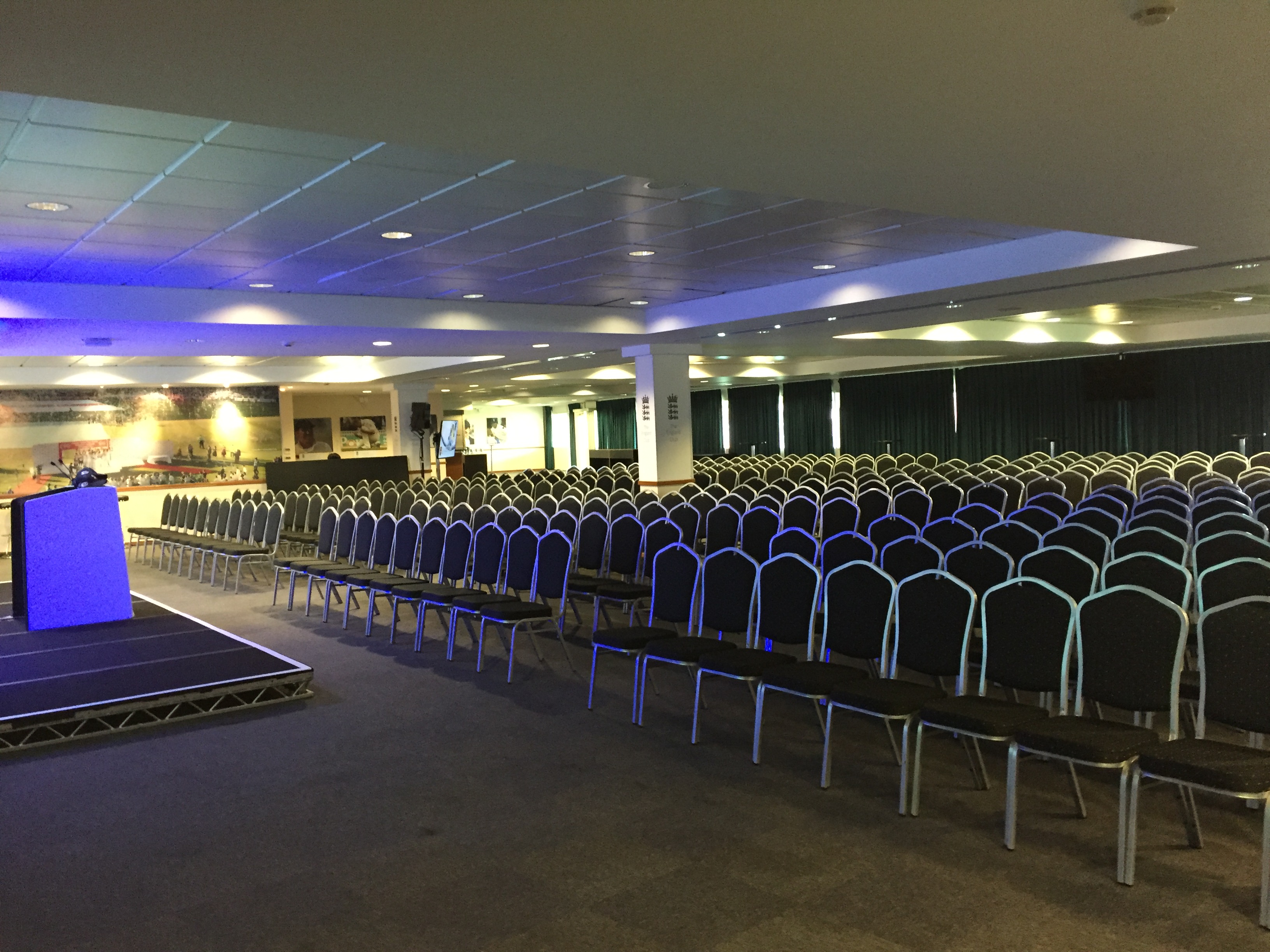 Spacious Kia Oval England Room set for conferences with arranged chairs and stage.