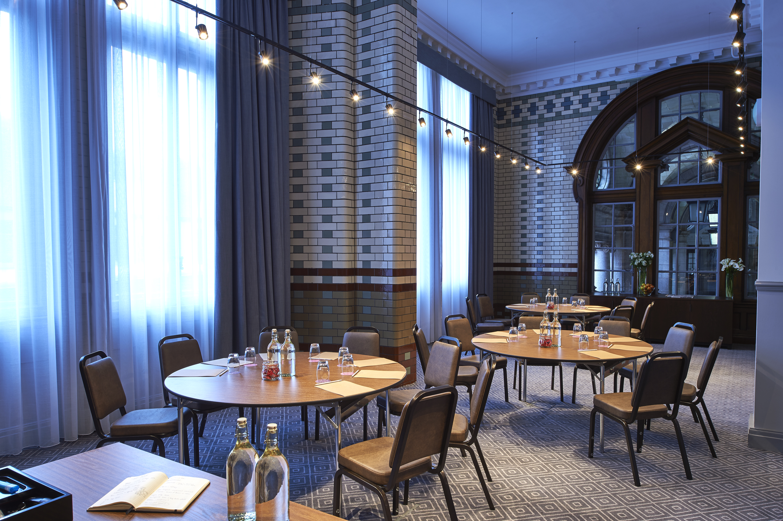 Elegant meeting space with round tables at Kimpton Clocktower Hotel for workshops and conferences.