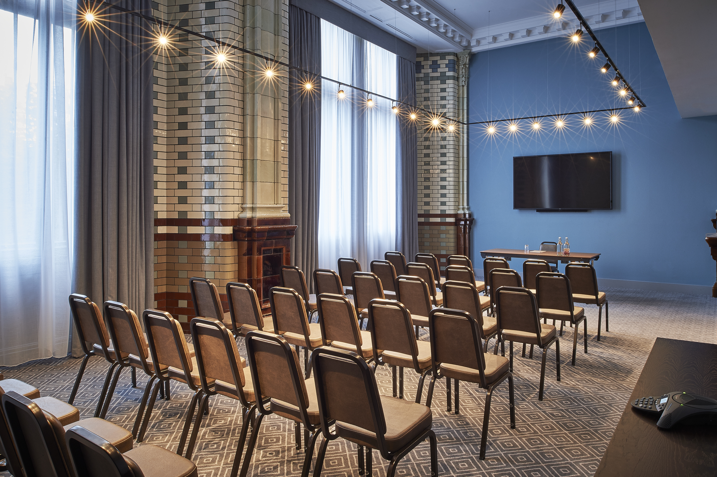 Elegant meeting space at Kimpton Clocktower Hotel with ambient lighting and presentation screen.