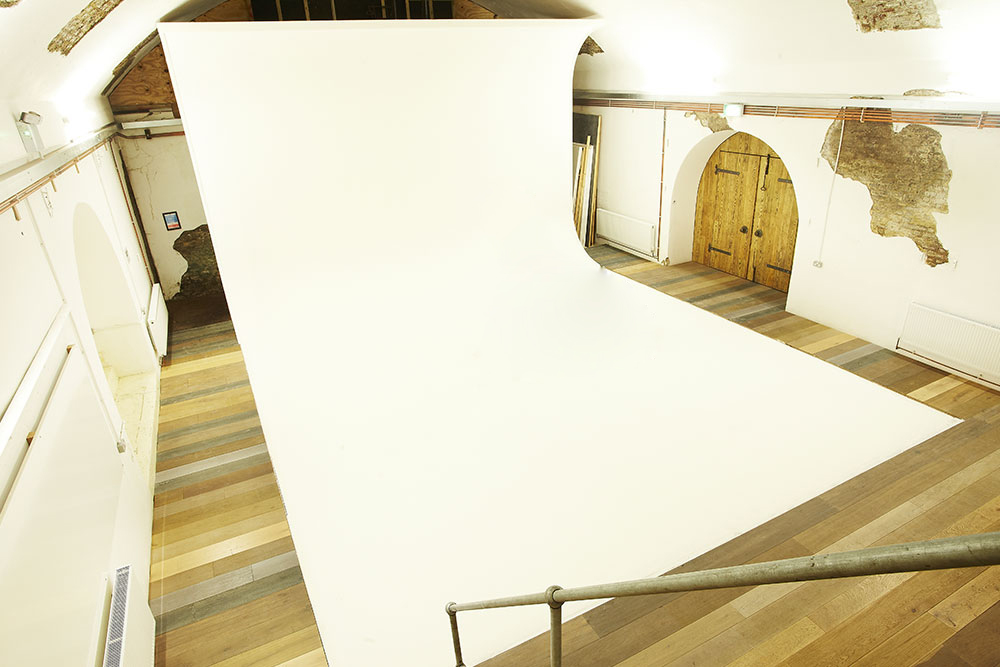 Versatile event space with seamless white backdrop, ideal for workshops and presentations.