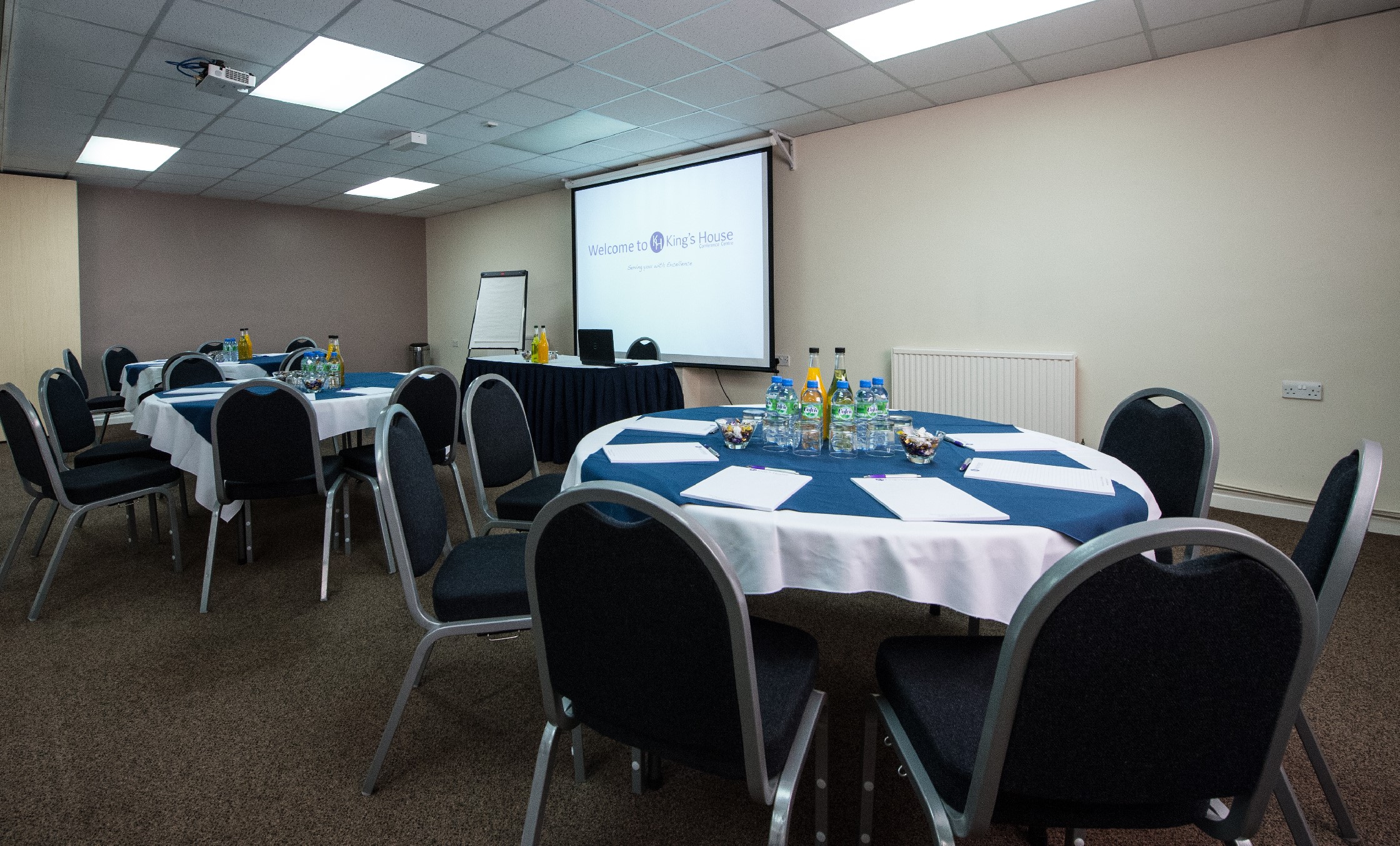 Seminar Room 3/4 at King's House, featuring round tables for professional events.