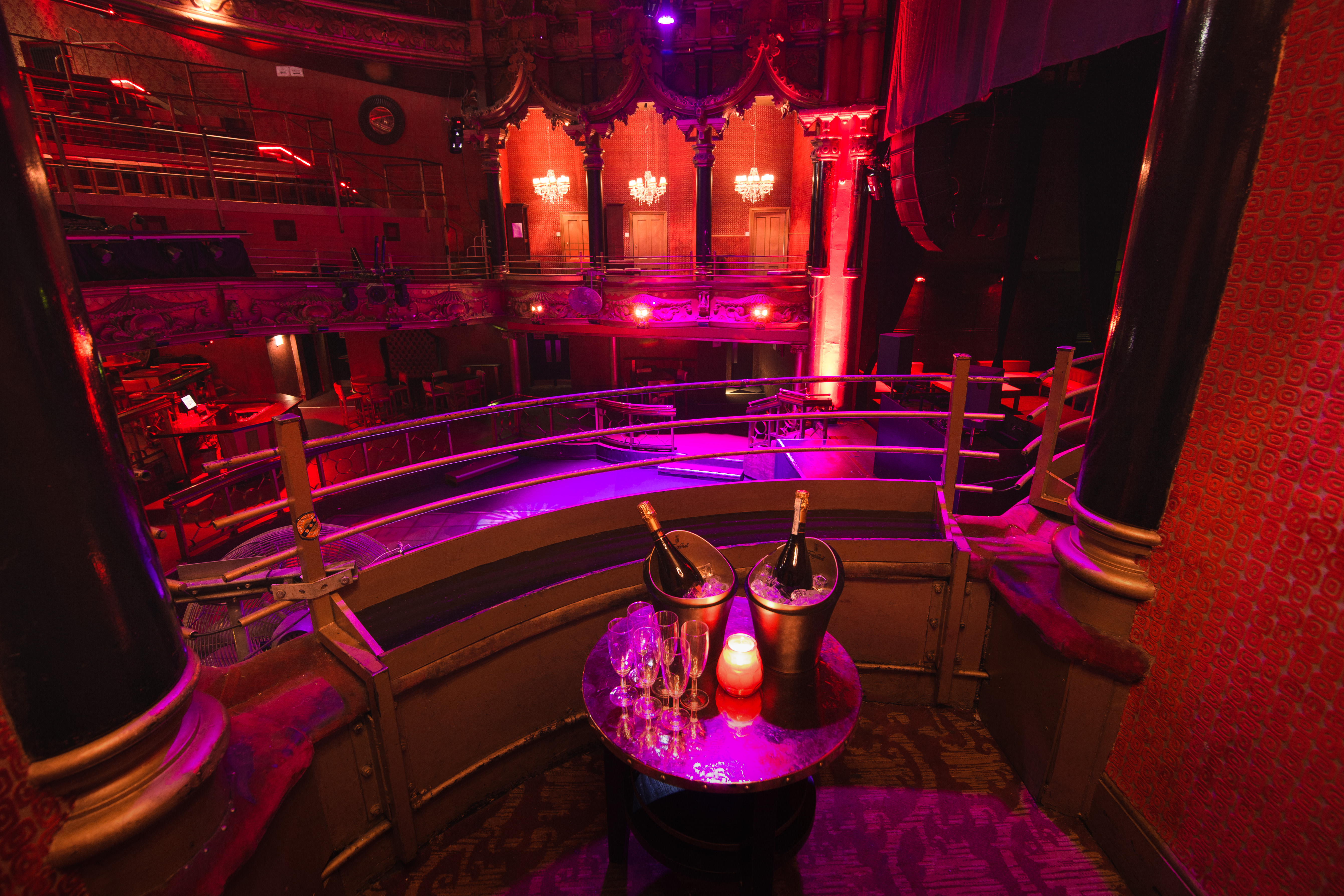 Elegant event space in The Grand with stage, ambient lighting, and champagne for celebrations.