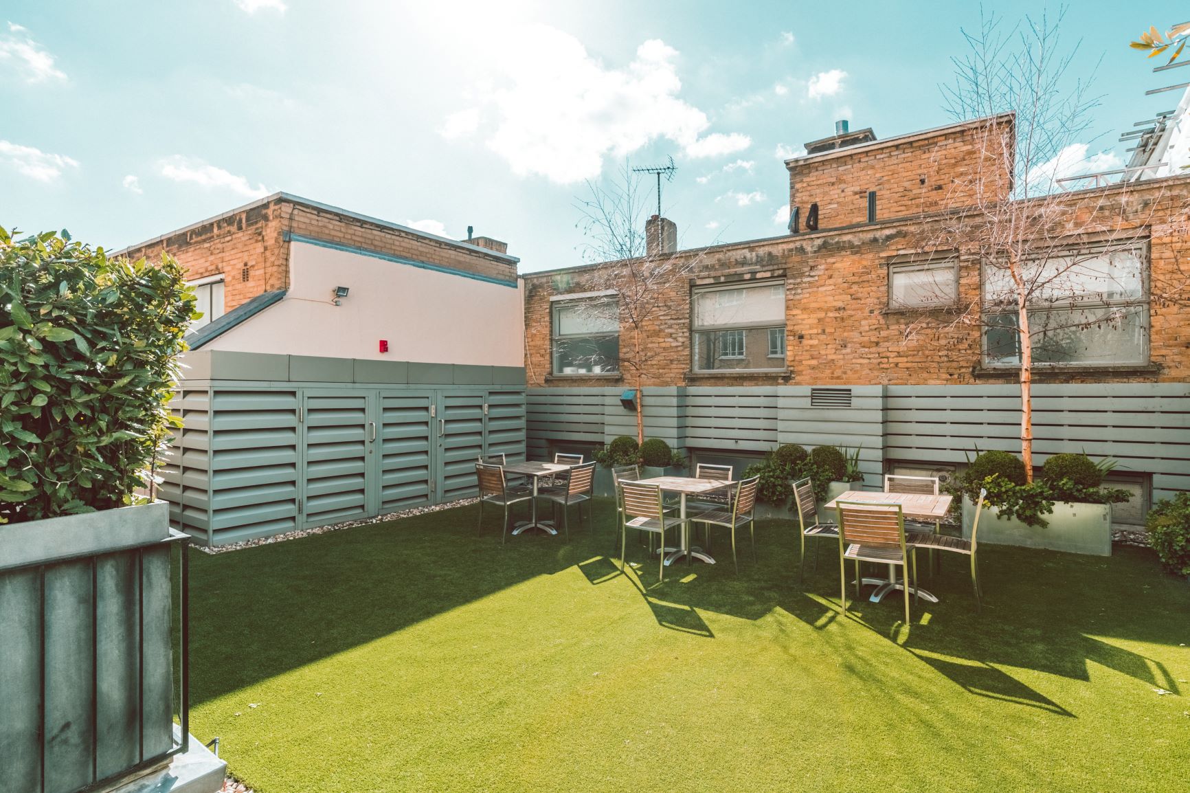 Outdoor networking space at 41 Portland Place with modern furniture and greenery.