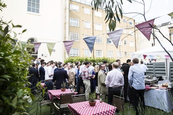 Outdoor networking event at Ann Rylands & Terrace with colorful bunting and food stations.