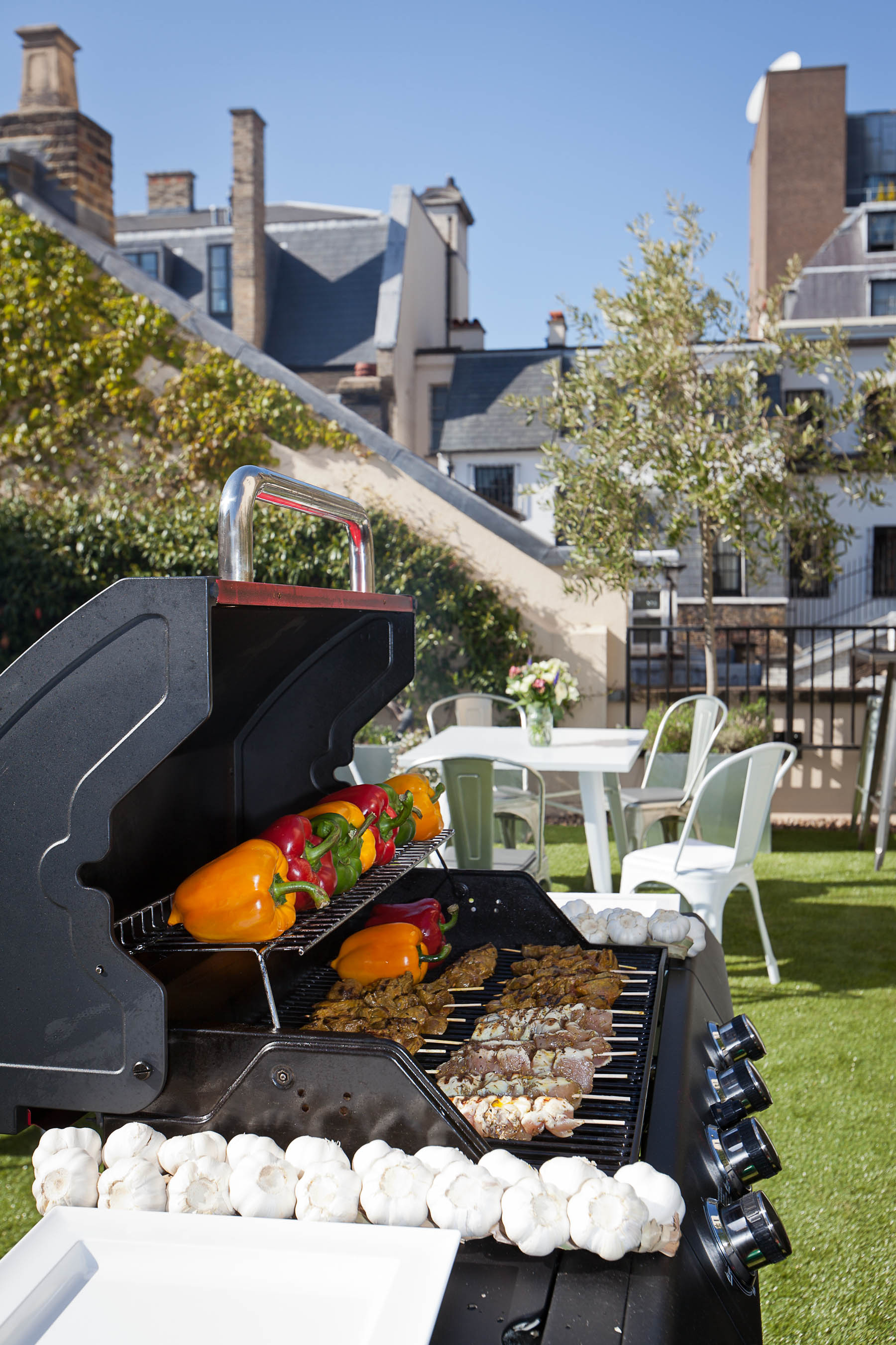 Outdoor networking event at Ann Rylands & Terrace with vibrant grill and greenery.