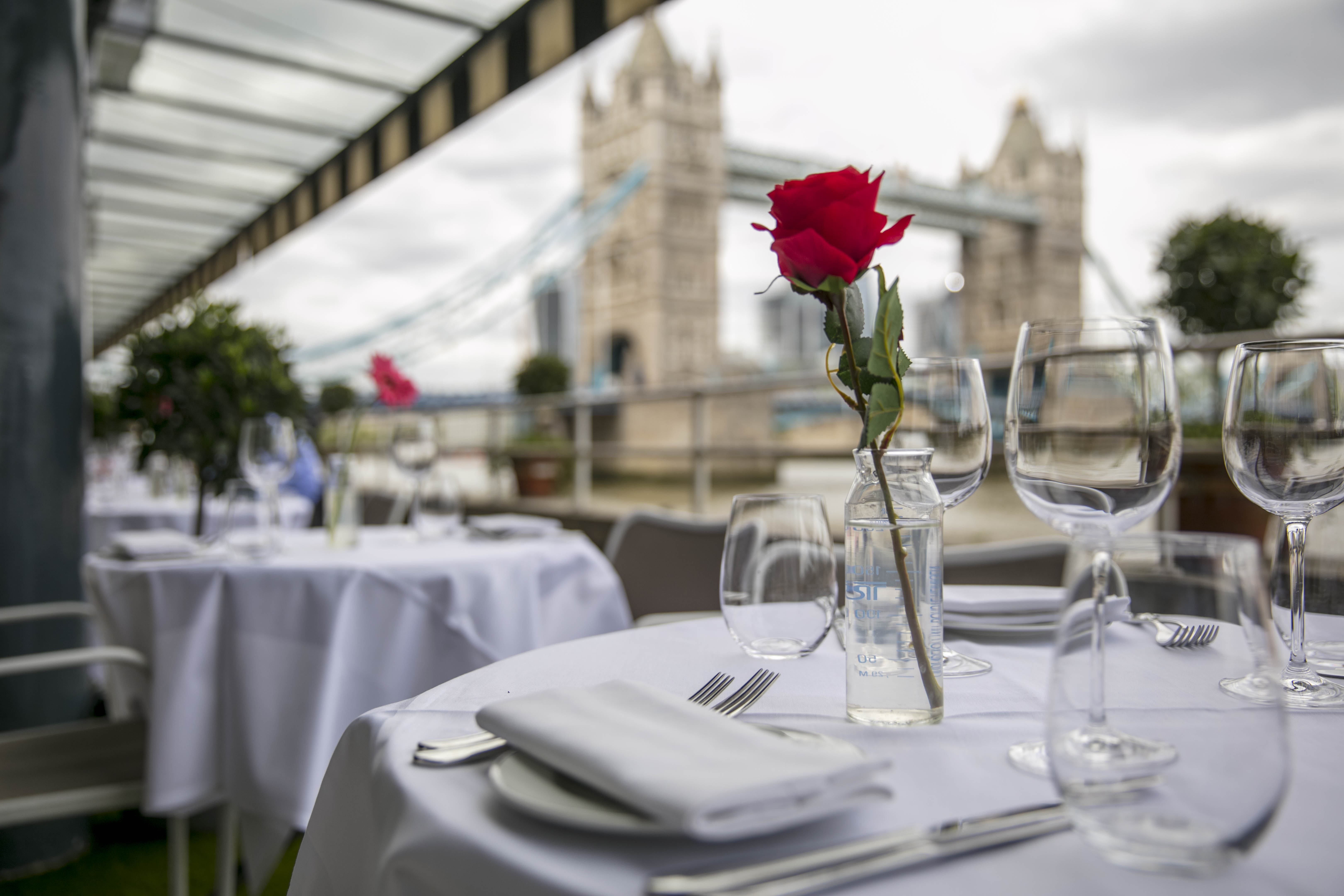 Elegant dining setup with rose centerpiece at Butlers Wharf, overlooking Tower Bridge.