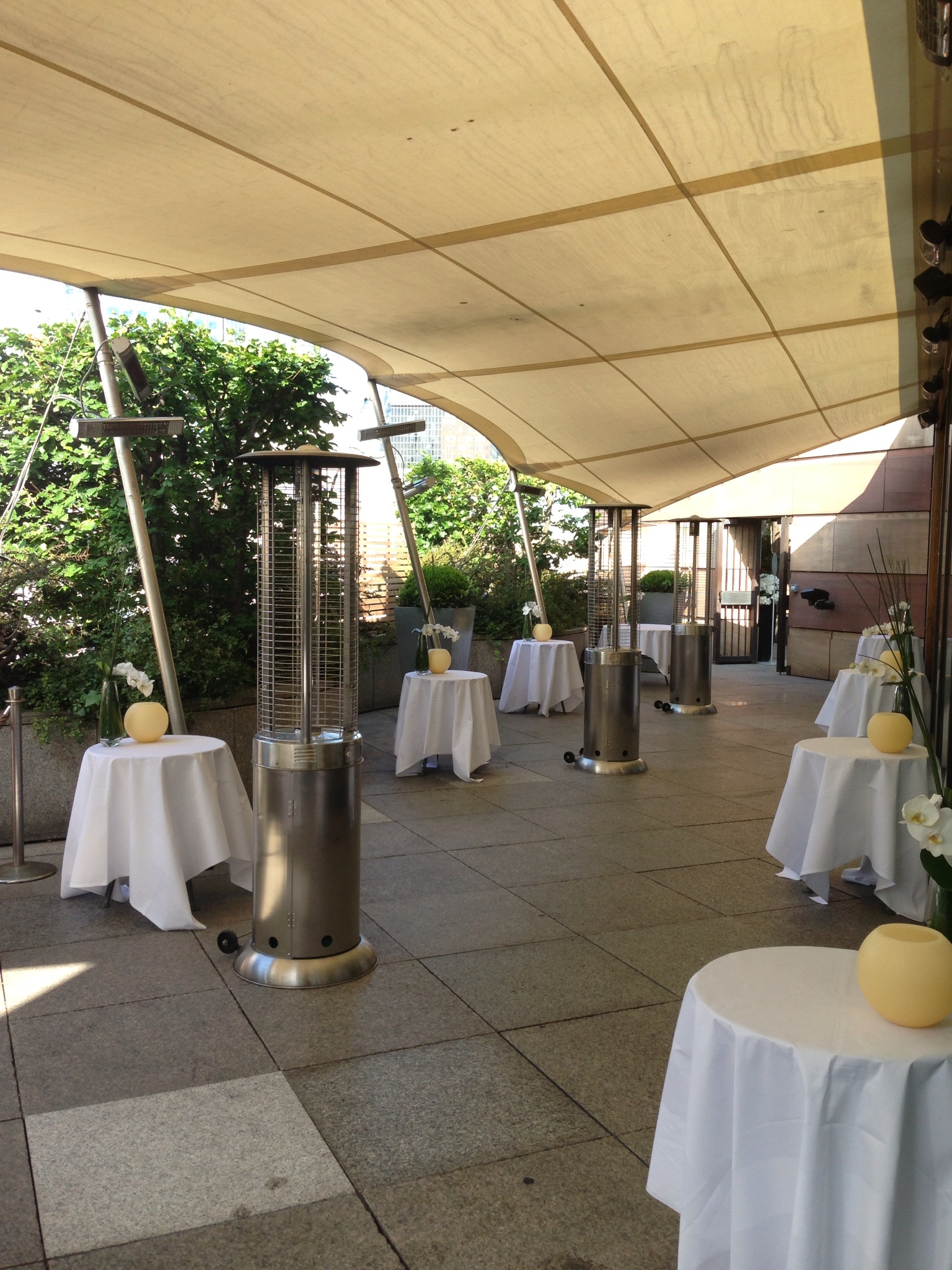 Stylish outdoor event space at Coq d'Argent with round tables and elegant centerpieces.
