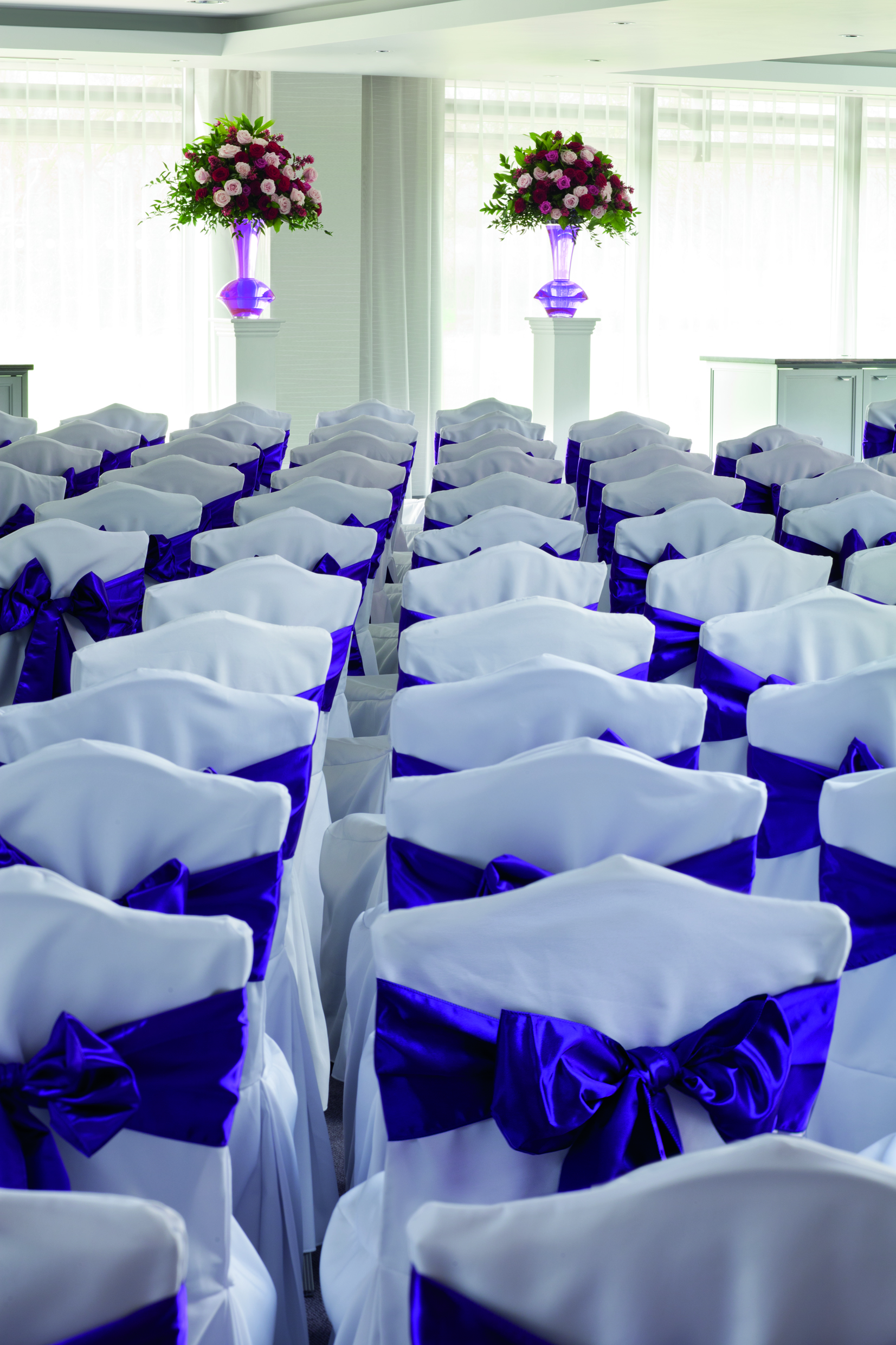 Elegant white chairs with purple sashes for weddings at Hilton London Syon Park.