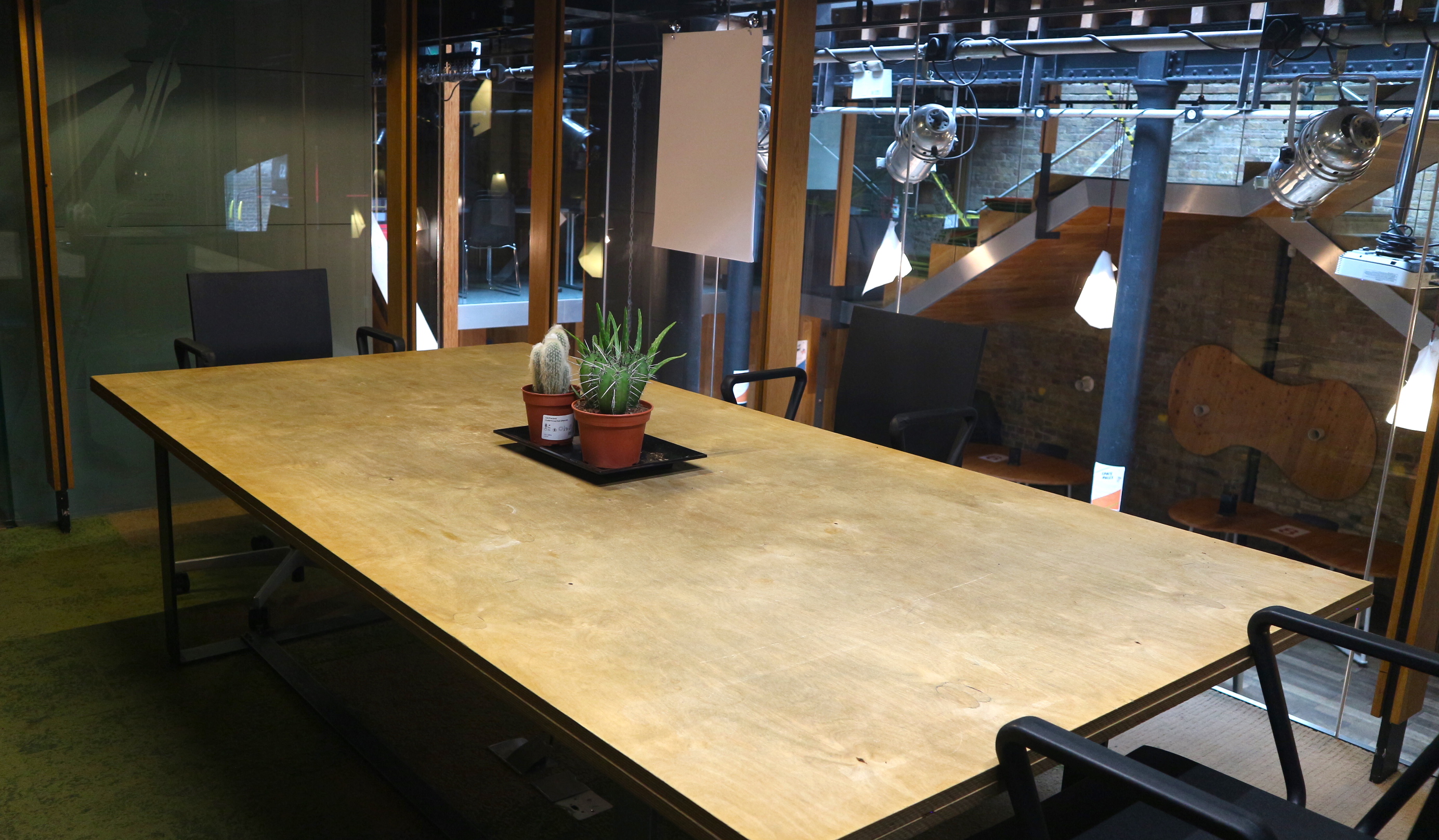 Modern meeting space at The Glasshouse, featuring a large wooden table and greenery.