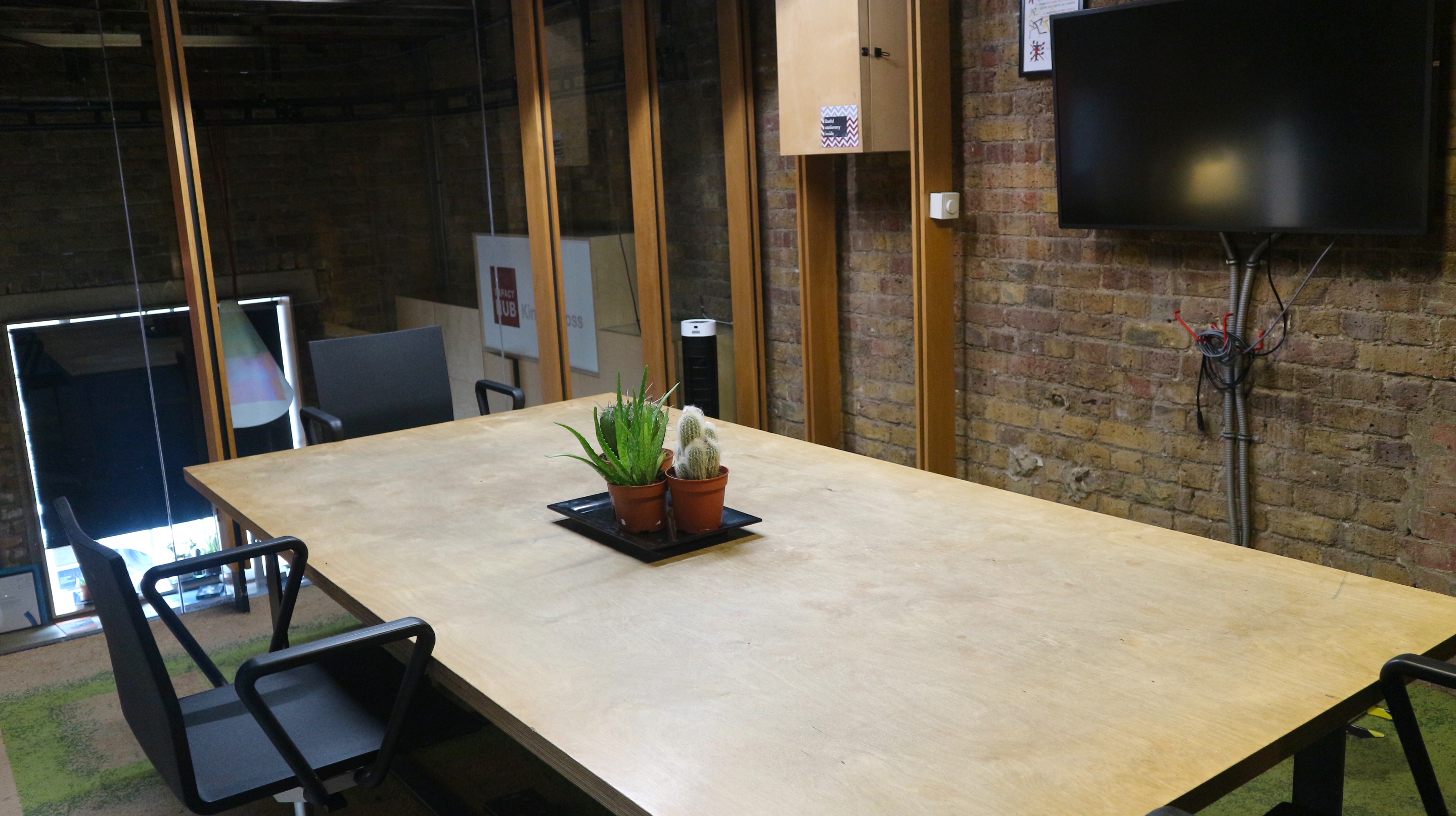 Modern meeting room with wooden table, ideal for collaborative discussions at Impact Hub.