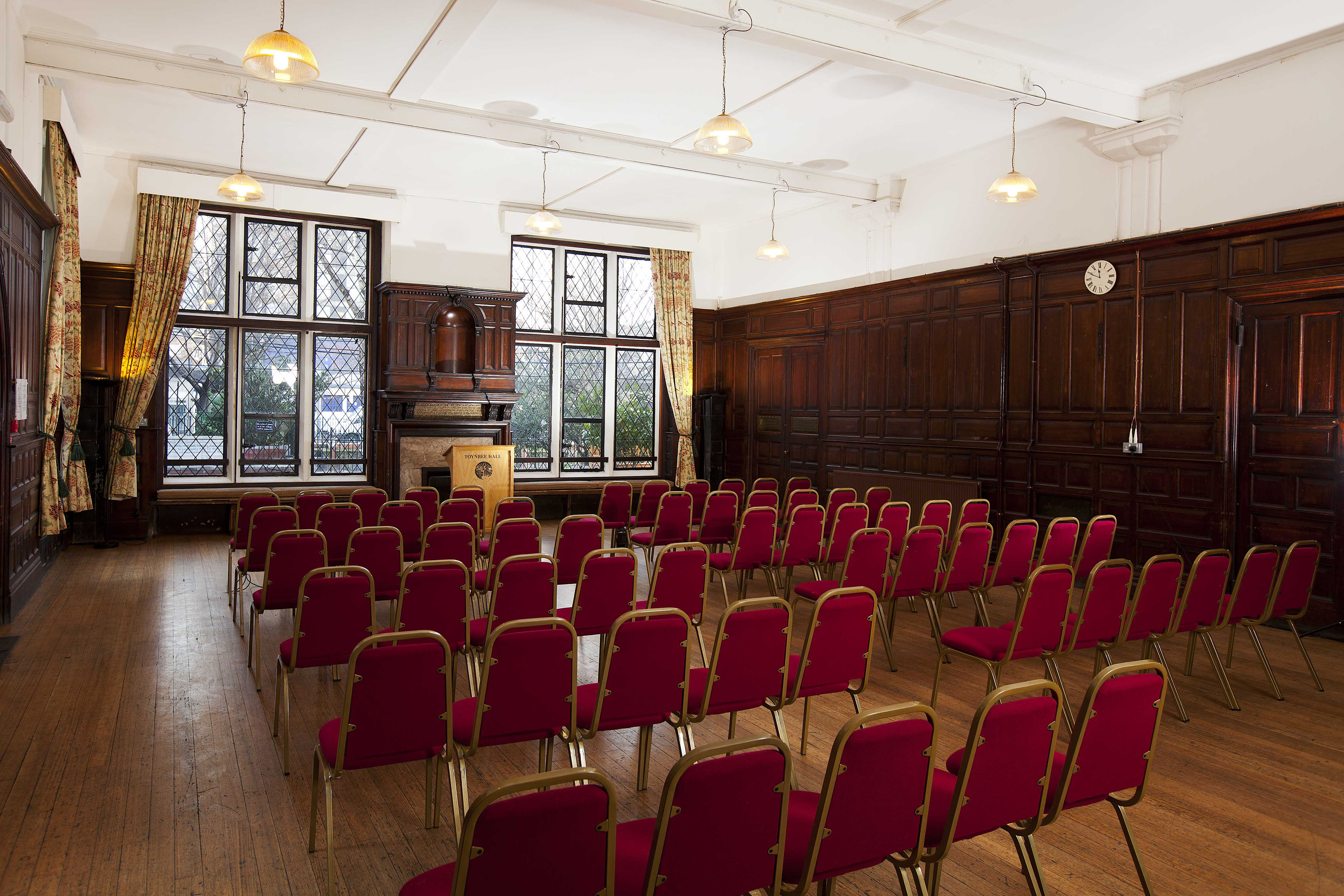 Lecture Hall at Toynbee Hall with red chairs, ideal for presentations and workshops.