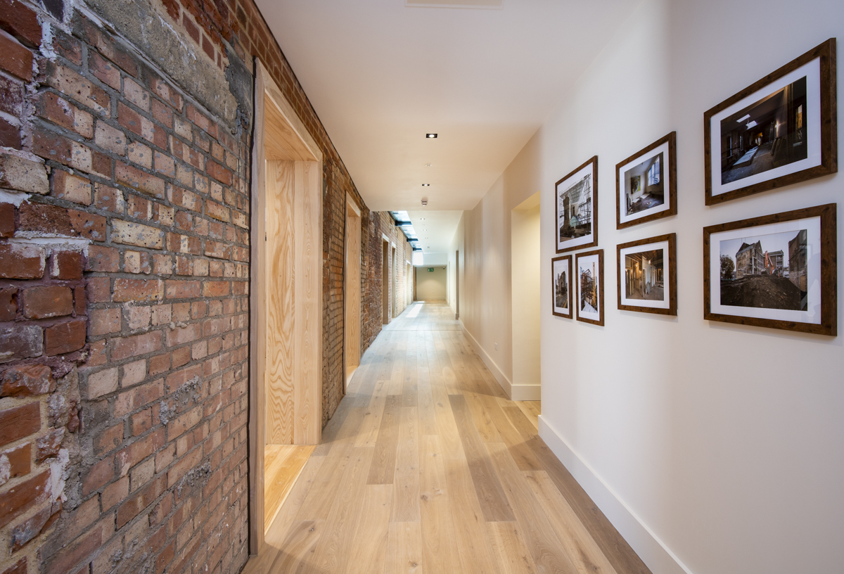 Modern corridor in Toynbee Hall, ideal for networking events with exposed brick and wood.