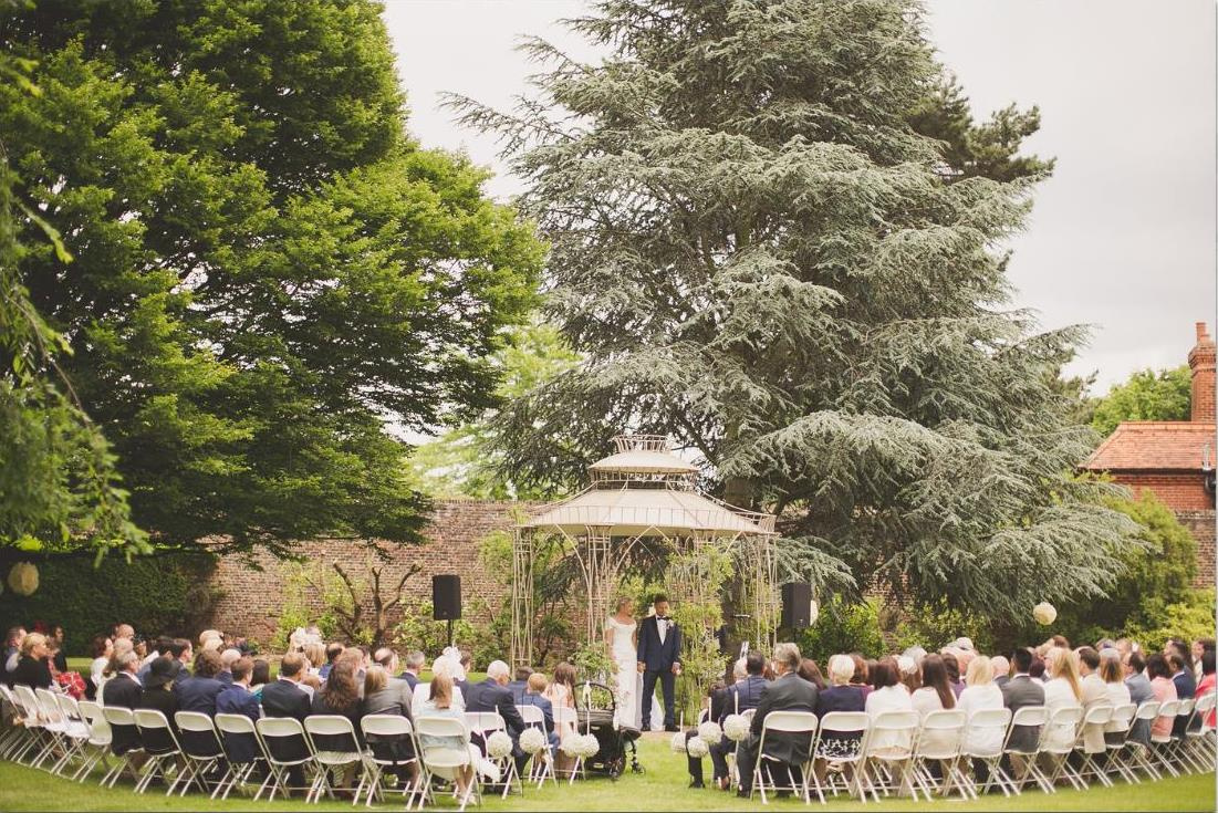 Outdoor wedding ceremony in The Garden Room, Hampton Court Palace with gazebo and lush greenery.