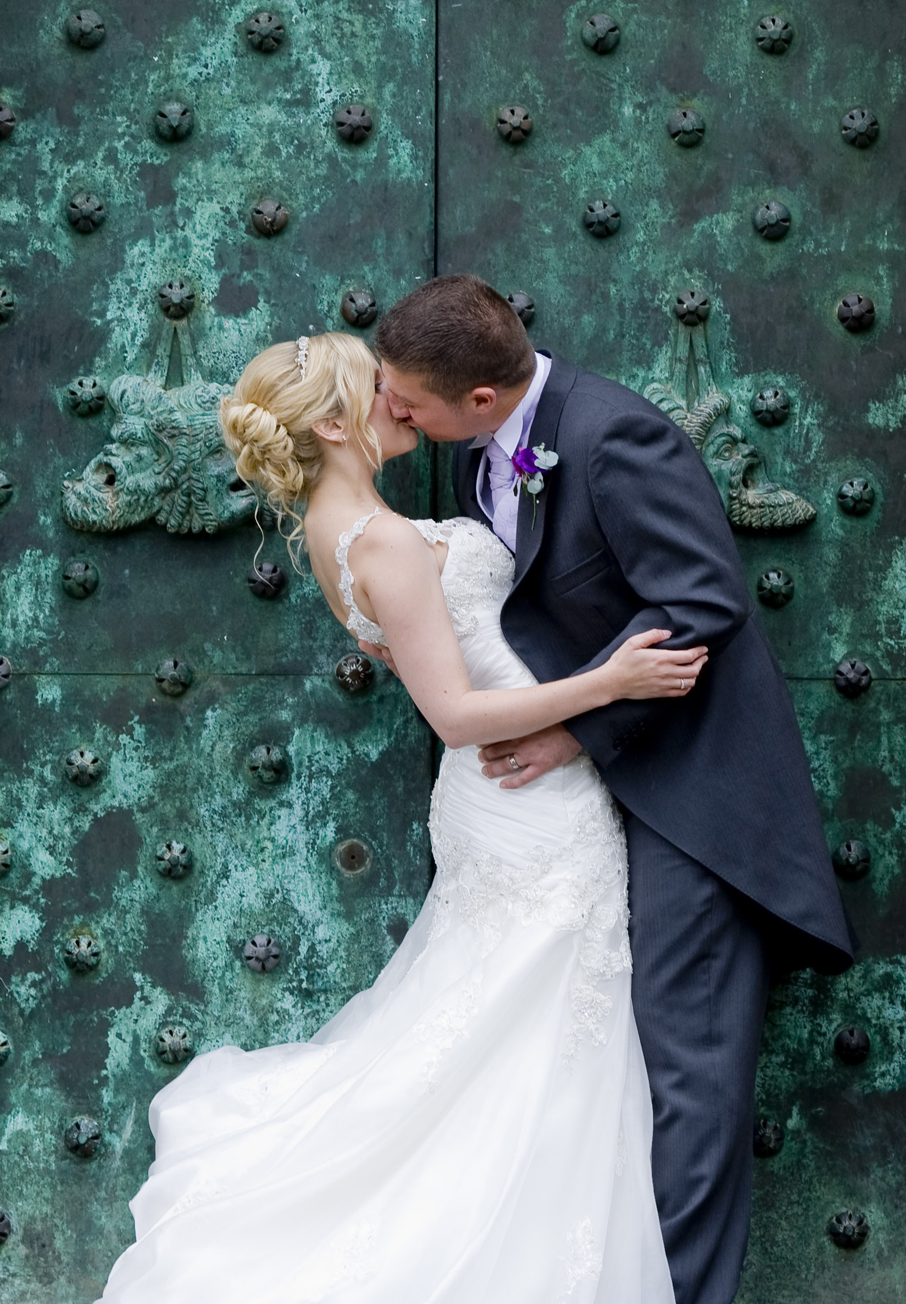 Couple kissing by ornate door at Port Lympne Hotel, perfect for wedding photography.