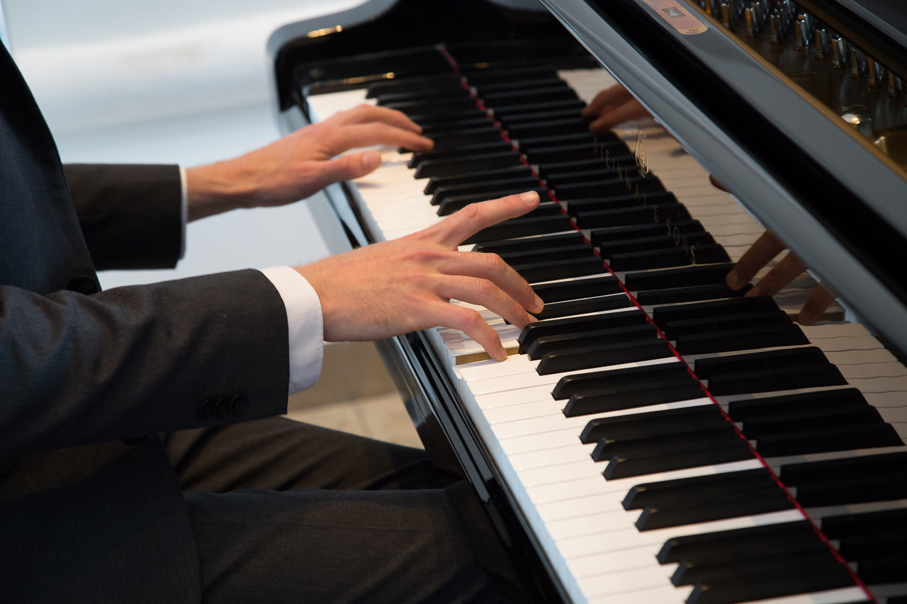 Pianist's hands playing grand piano at The Bridgewater Hall for elegant live music event.