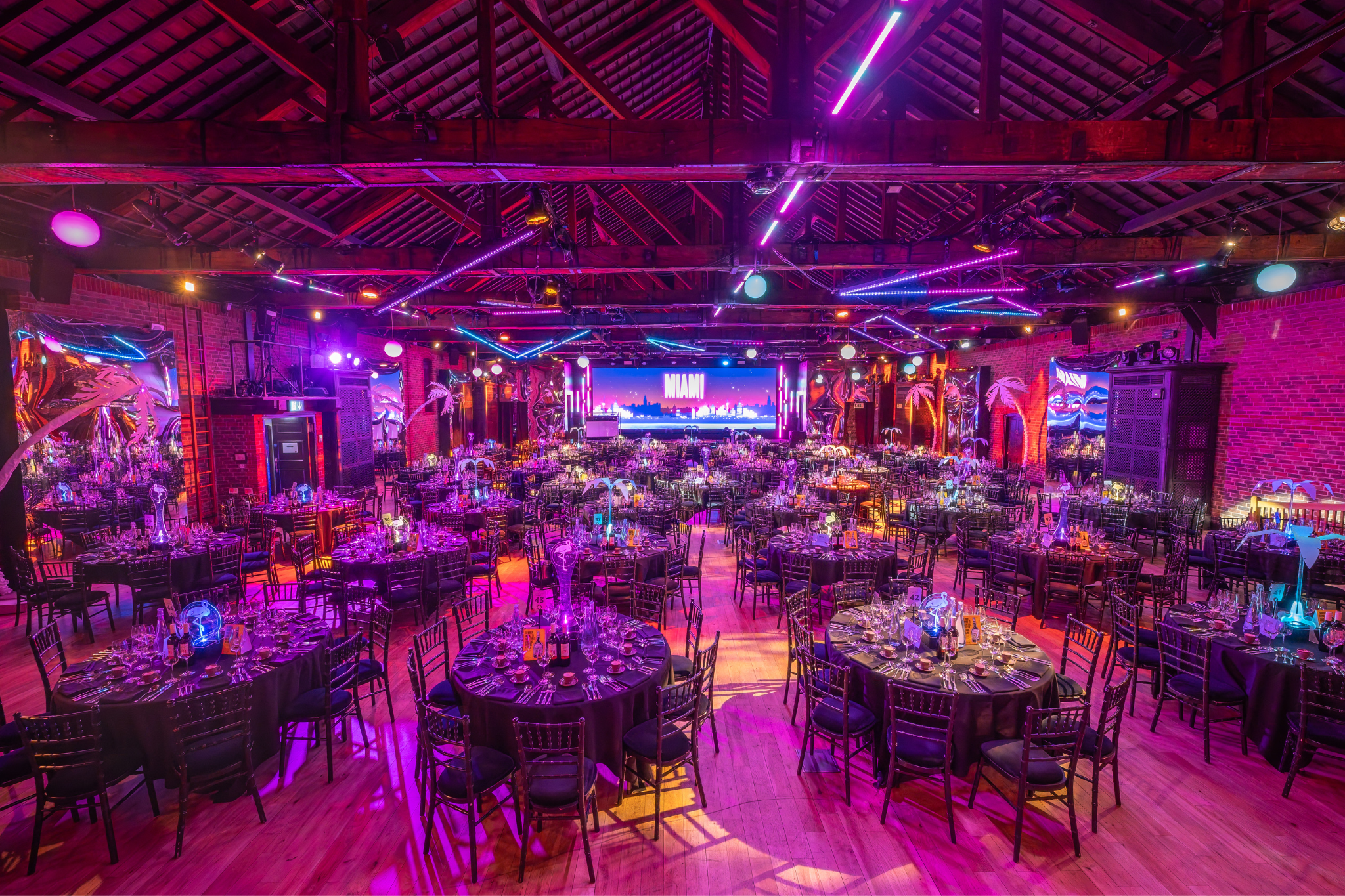 Elegant gala dinner setup at The Porter Tun, featuring floral centerpieces and vibrant lighting.