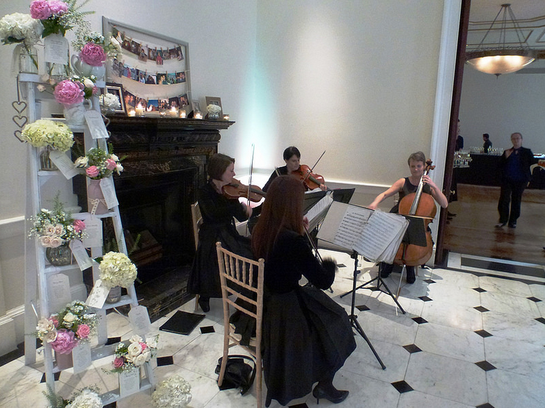 Marble Hall event space with string quartet near elegant fireplace for weddings and gatherings.