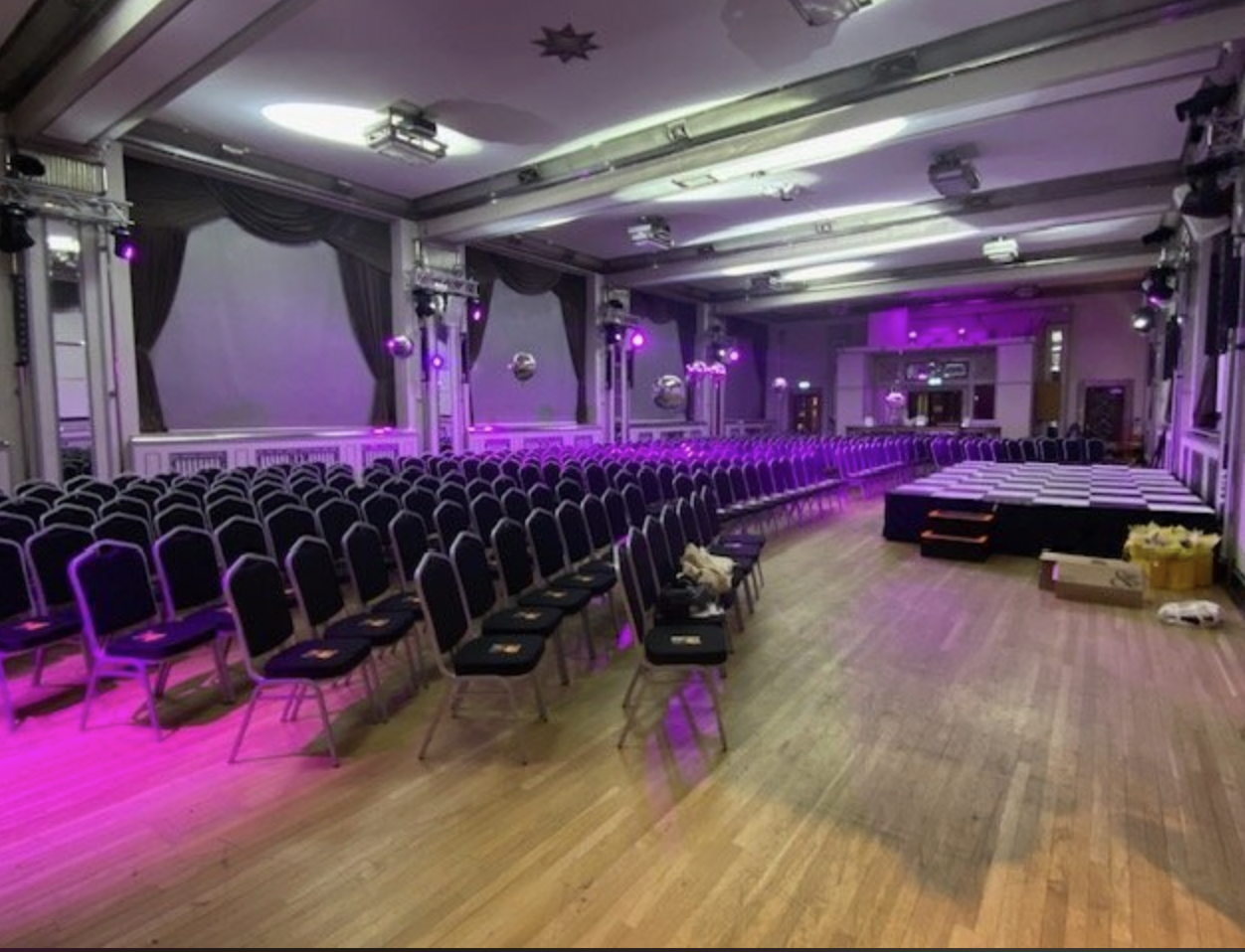 The Bloomsbury Ballroom conference setup with vibrant purple lighting and black chairs.