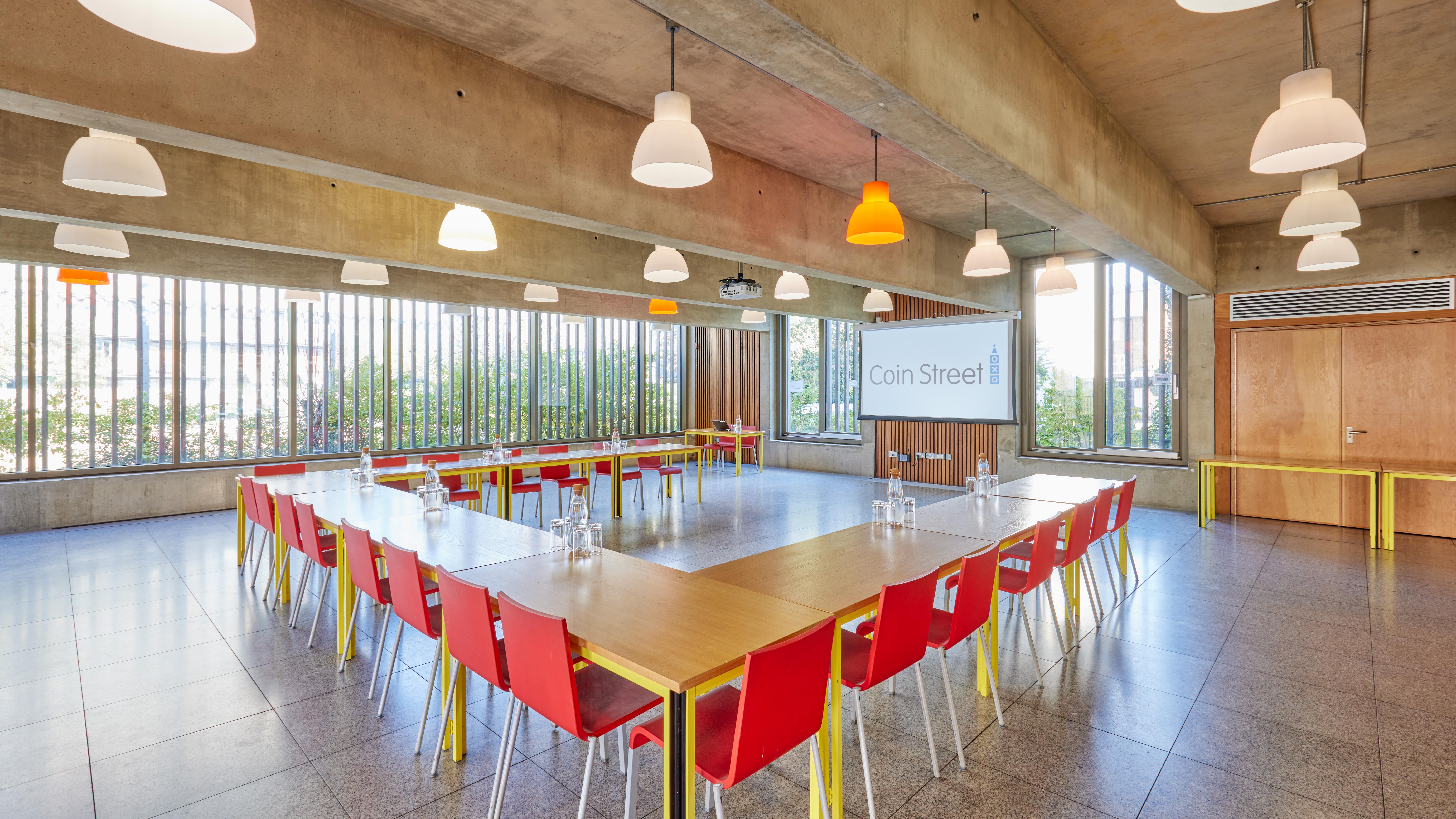 Modern meeting room with large table and colorful chairs, perfect for workshops.