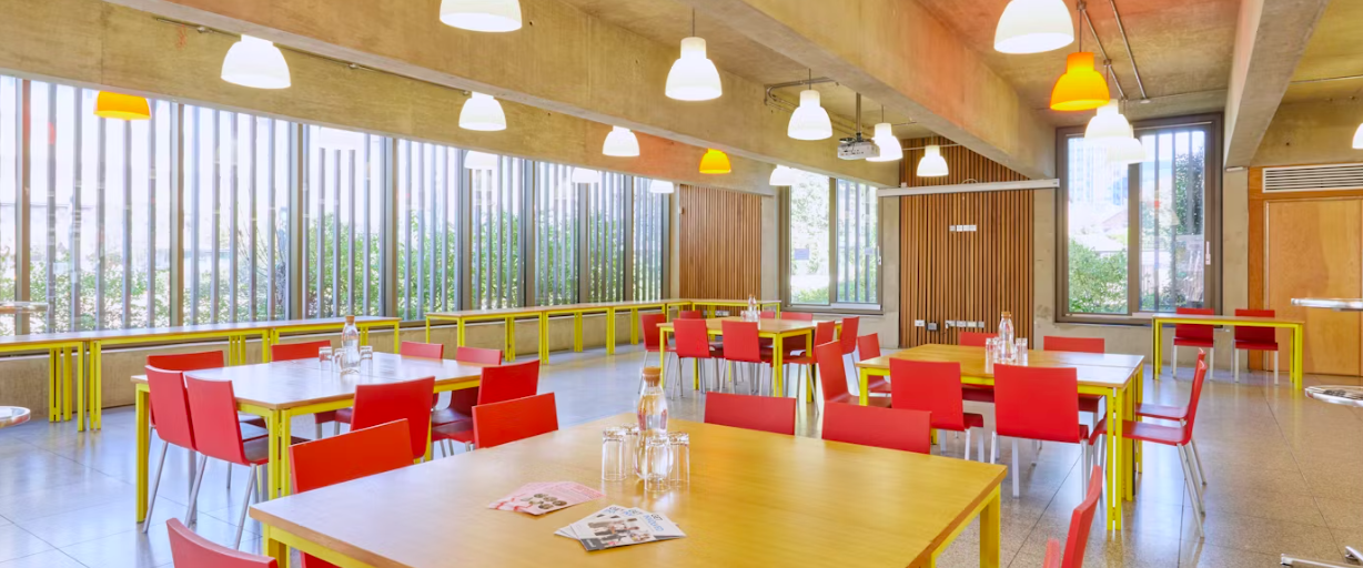 Modern dining space with red chairs at Coin Street Conference Centre for events and meetings.