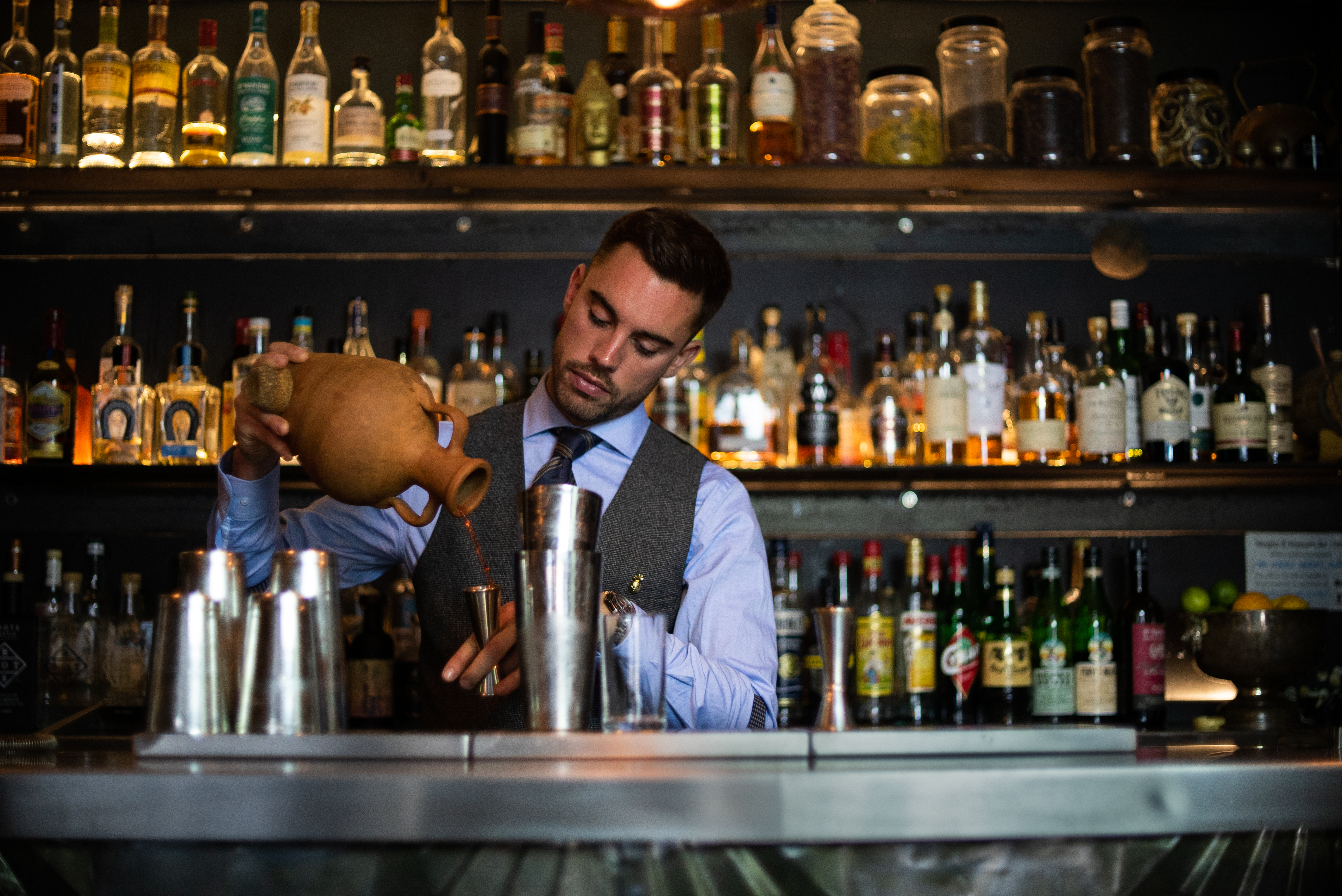 Bartender crafting cocktails at upscale Looking Glass Cocktail Club venue for events.