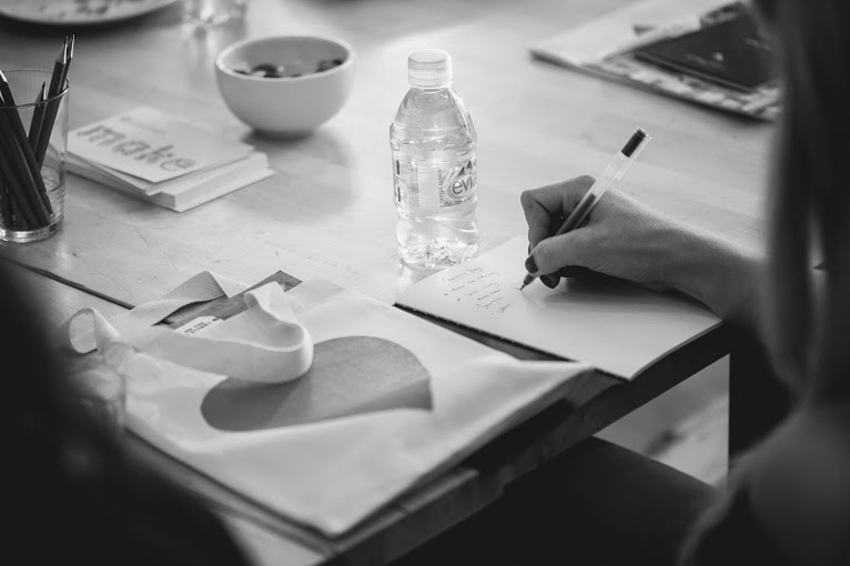 Focused meeting at The Make Lounge with engaged participant taking notes.