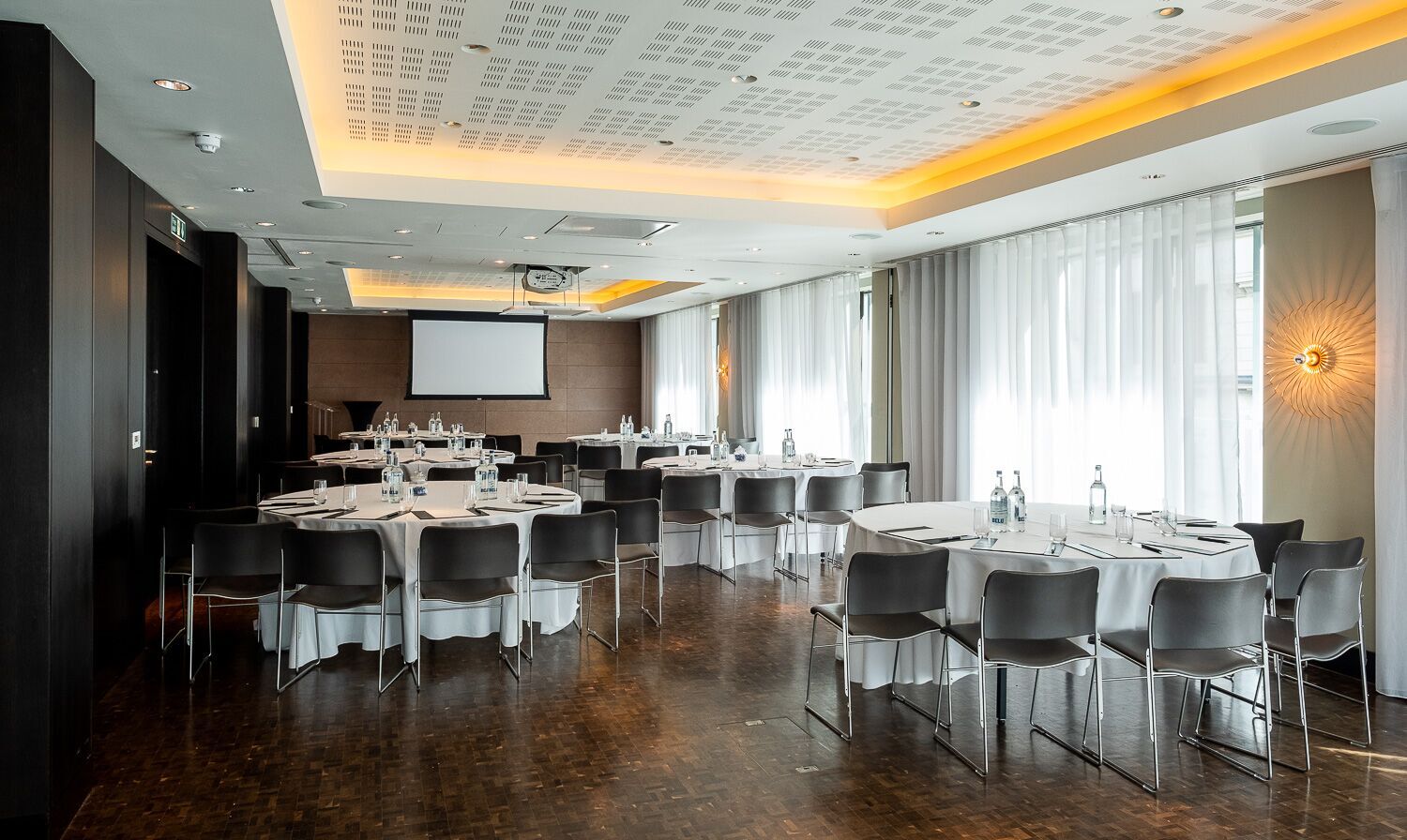 Versatile meeting space at South Place Hotel with round tables and central screen for events.