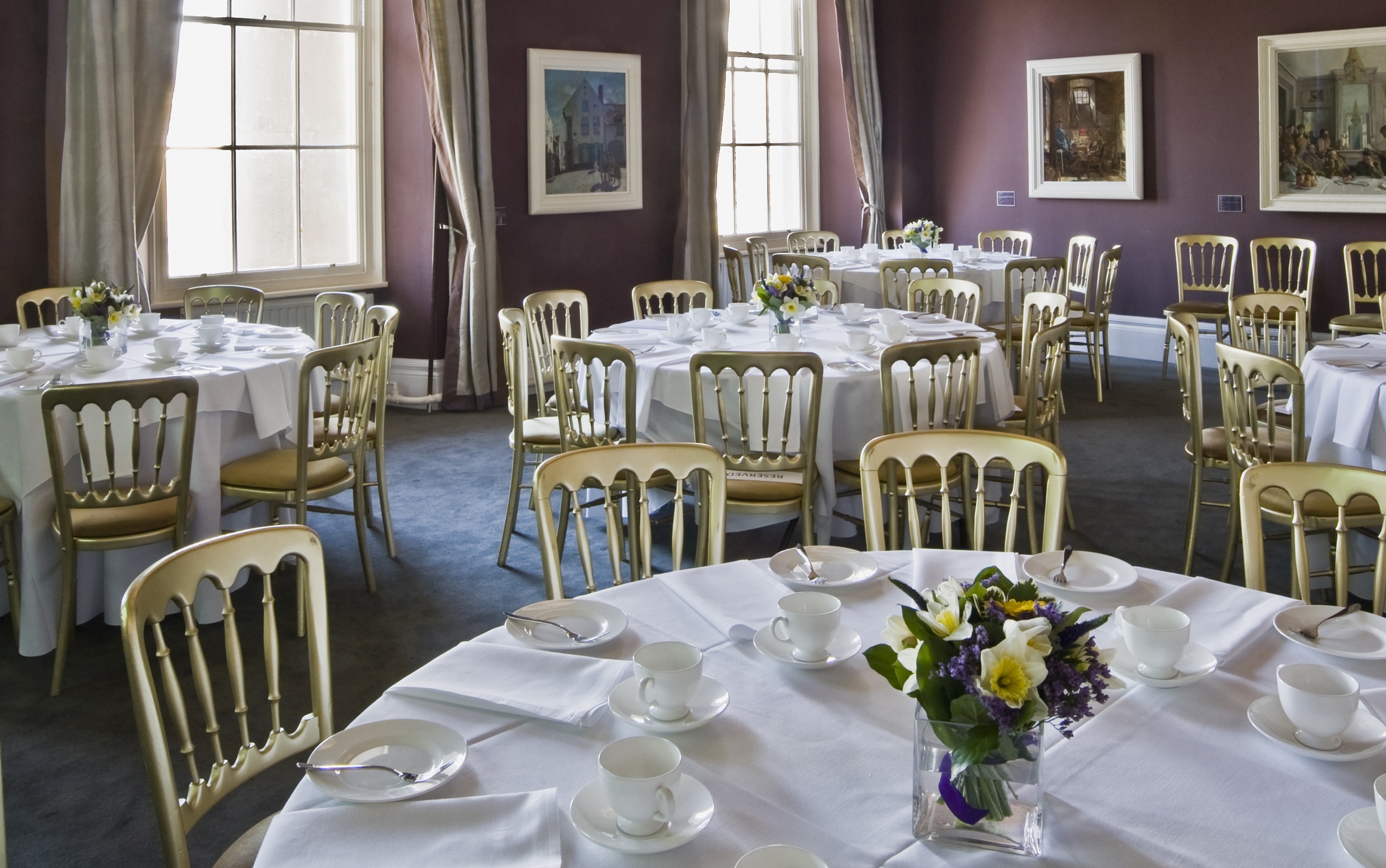 Orpen Boardroom at IWM London, elegant event space with round tables and floral centerpieces.