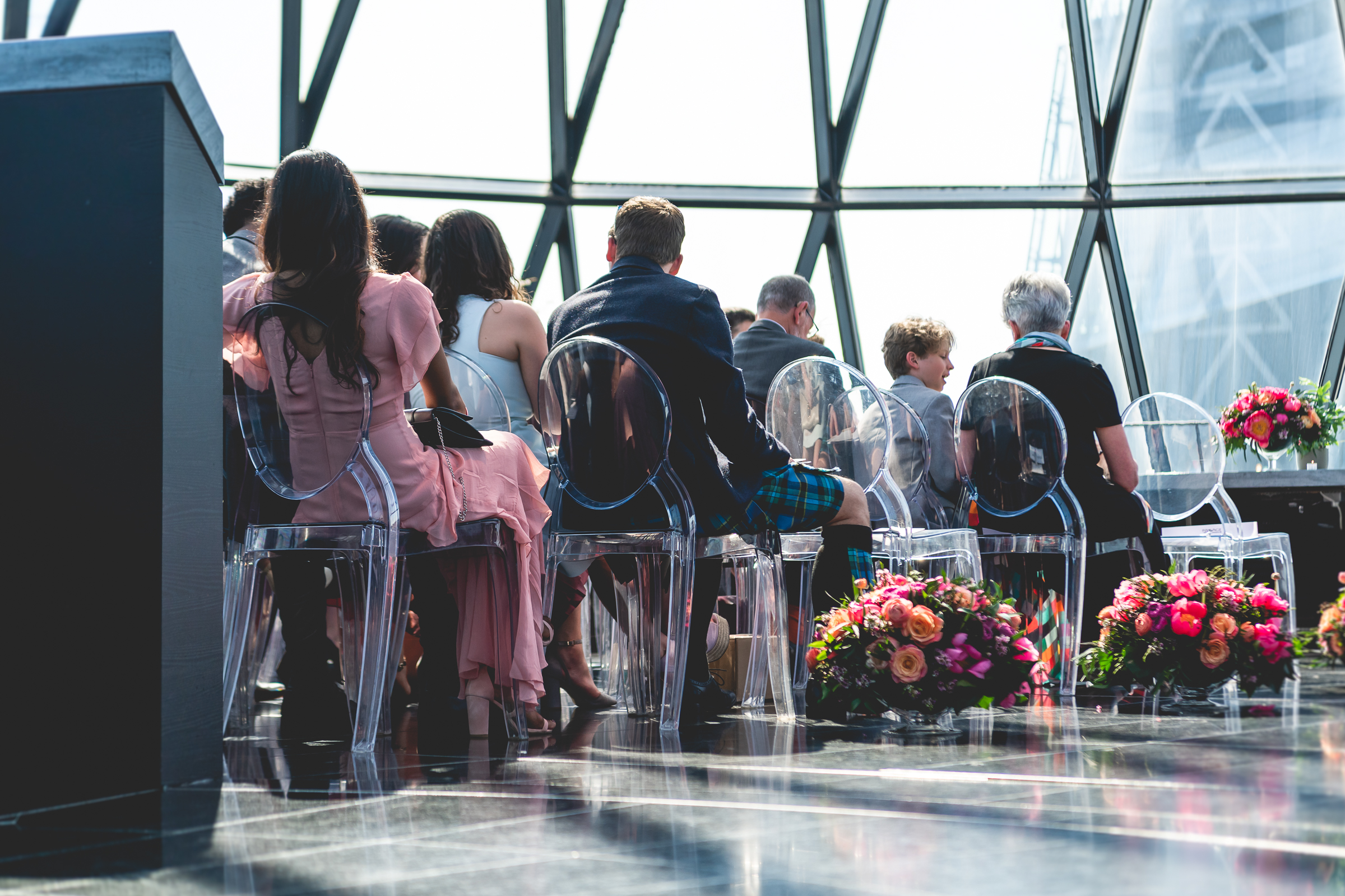 Elegant event setup at Searcys Gherkin with transparent chairs and vibrant floral arrangements.