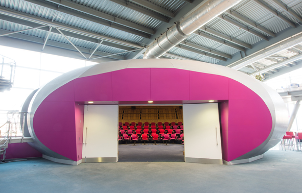 Modern auditorium with pink accents, ideal for conferences and workshops.