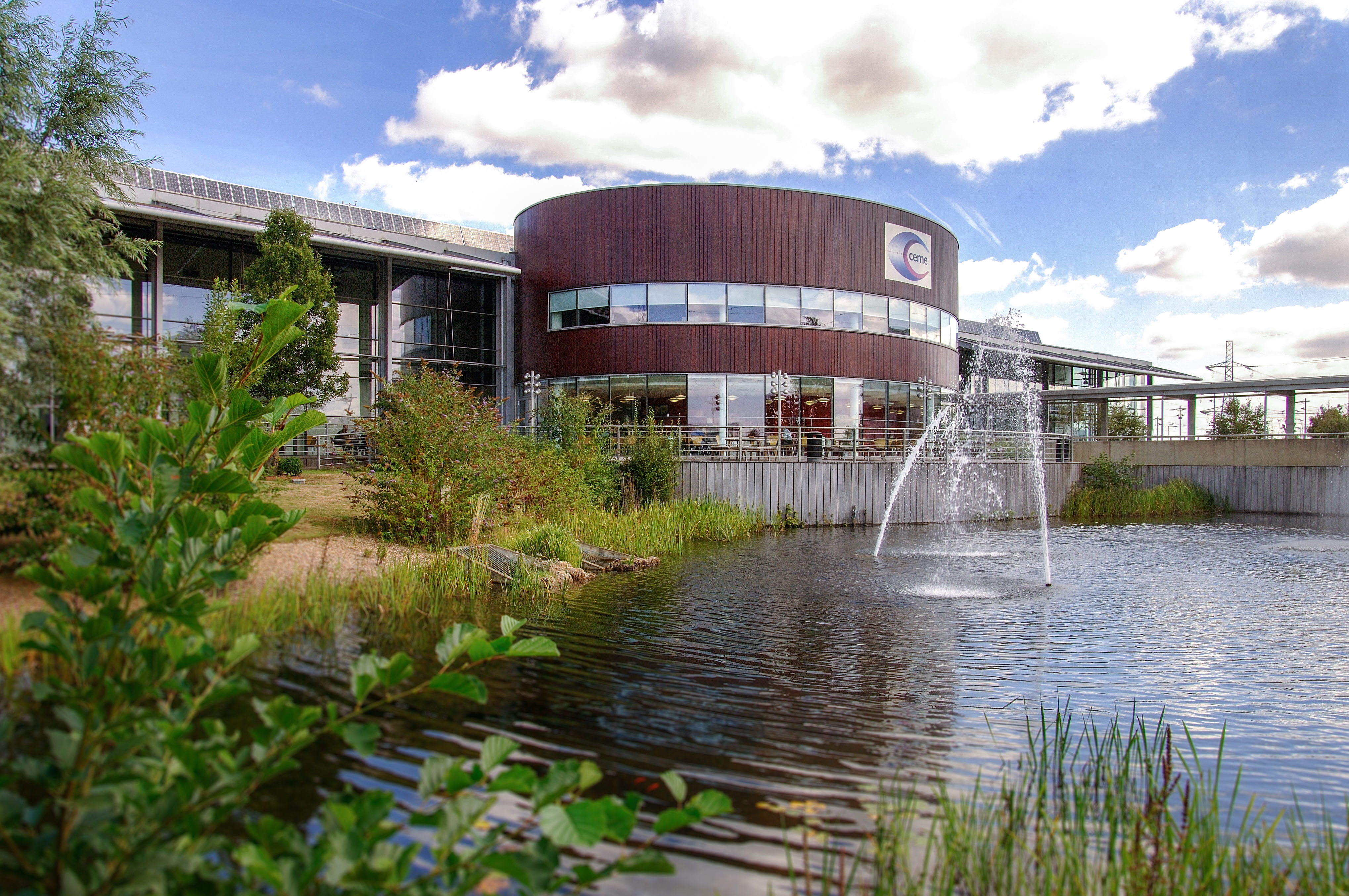 Modern event venue with greenery and water feature, ideal for corporate meetings and gatherings.