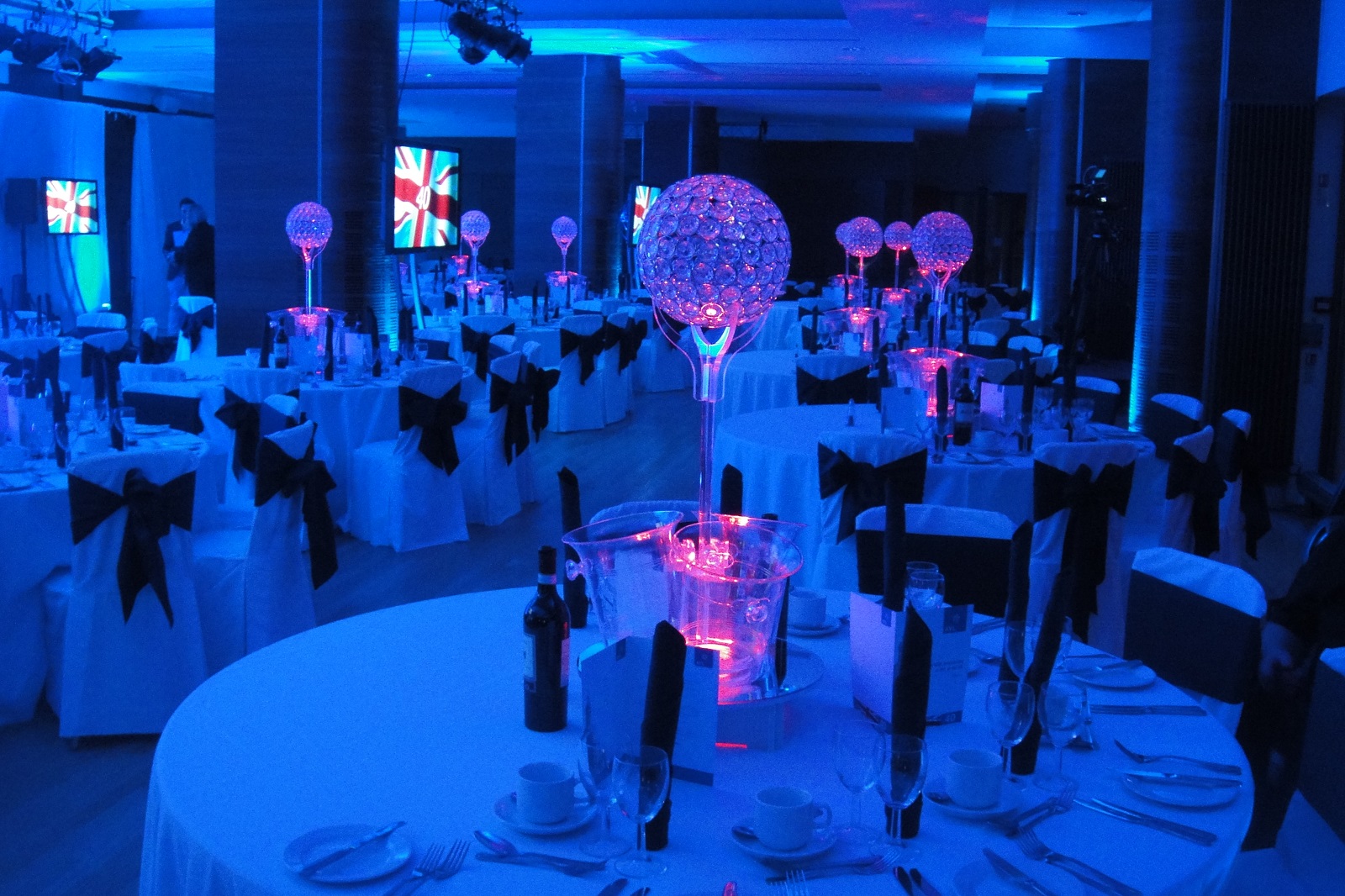 Elegant Queen's Tower Rooms set for formal event with blue lighting and multimedia screens.